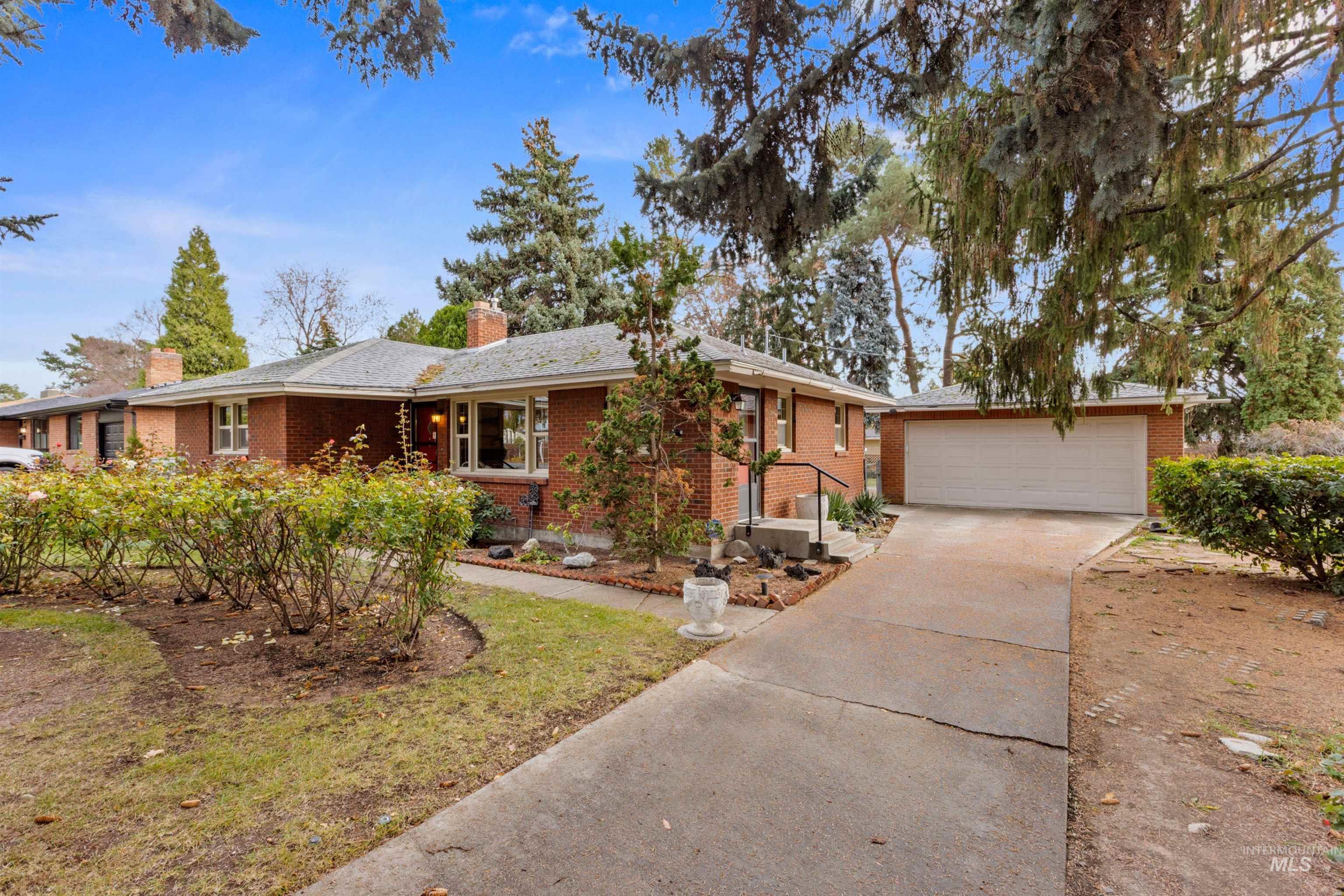 Single story home featuring driveway, brick siding, and a chimney