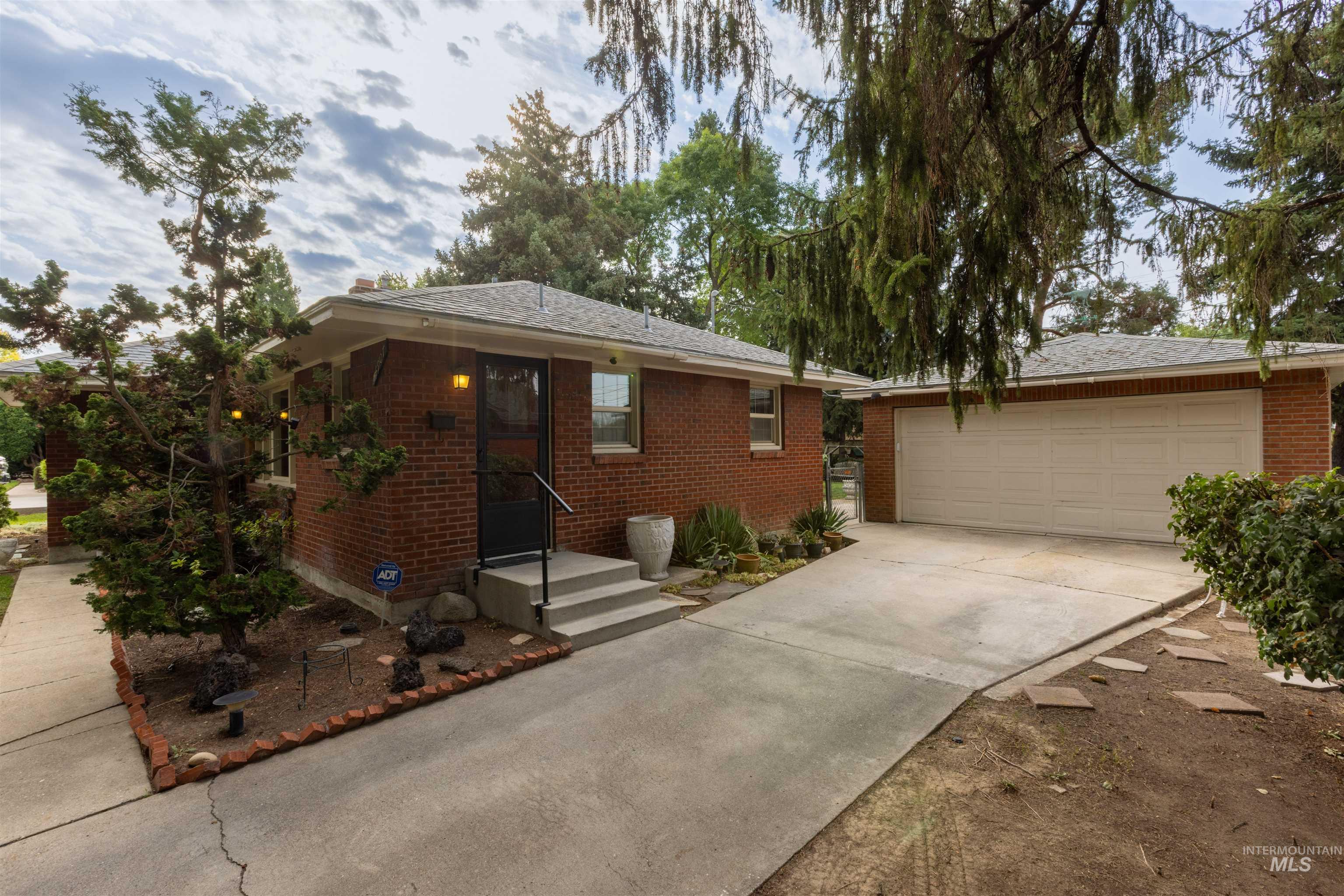 Ranch-style house featuring brick siding, a garage, concrete driveway, and roof with shingles