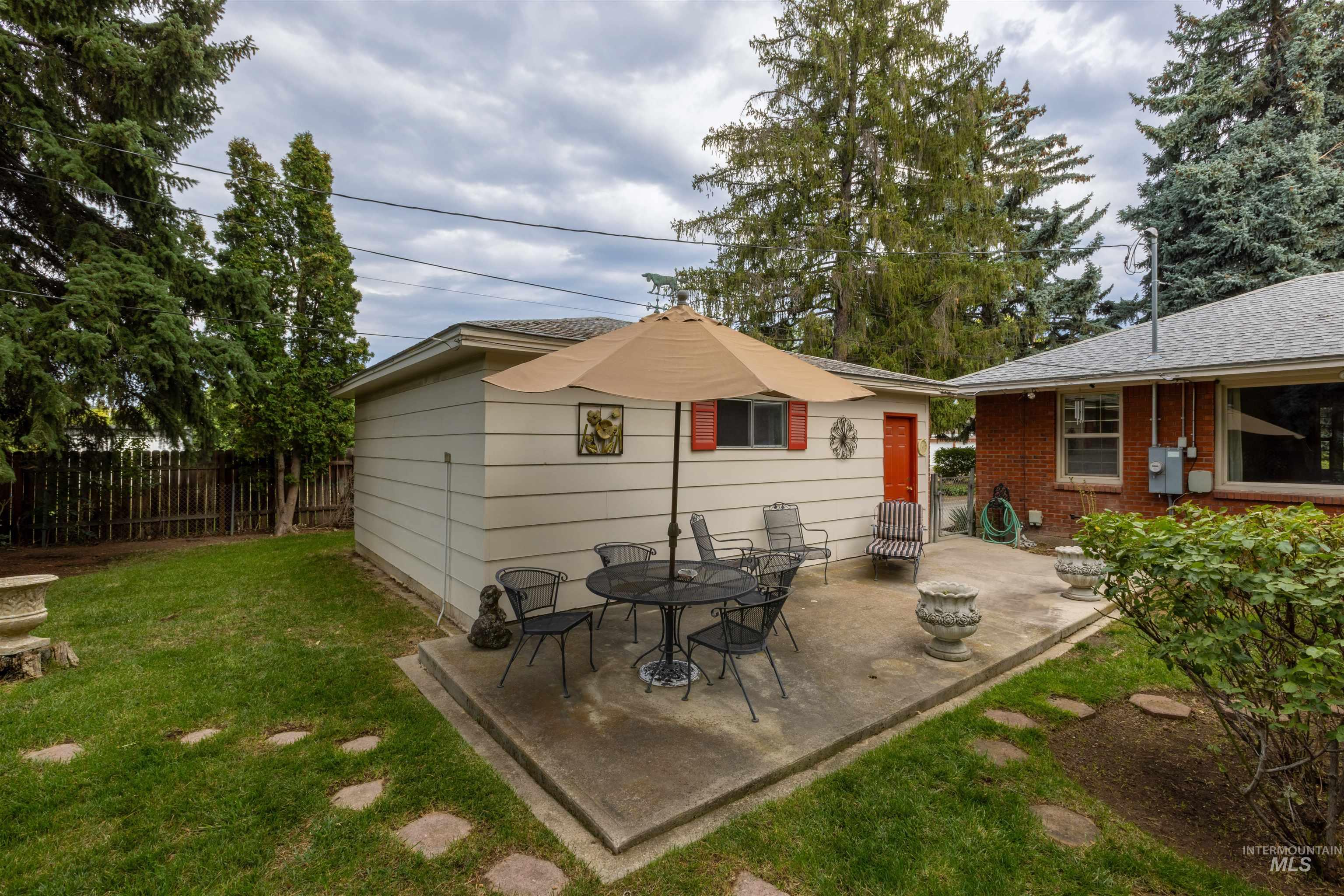 Rear view of house with a patio, a shingled roof, and an outdoor fire pit