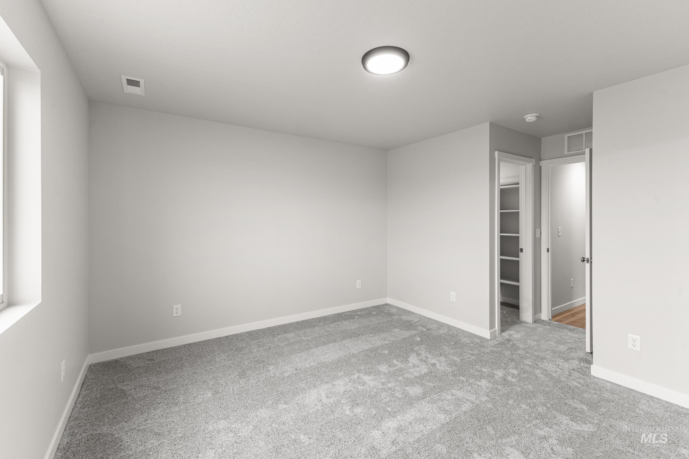 Spacious room featuring light gray carpeting, neutral wall paint, and white trim
