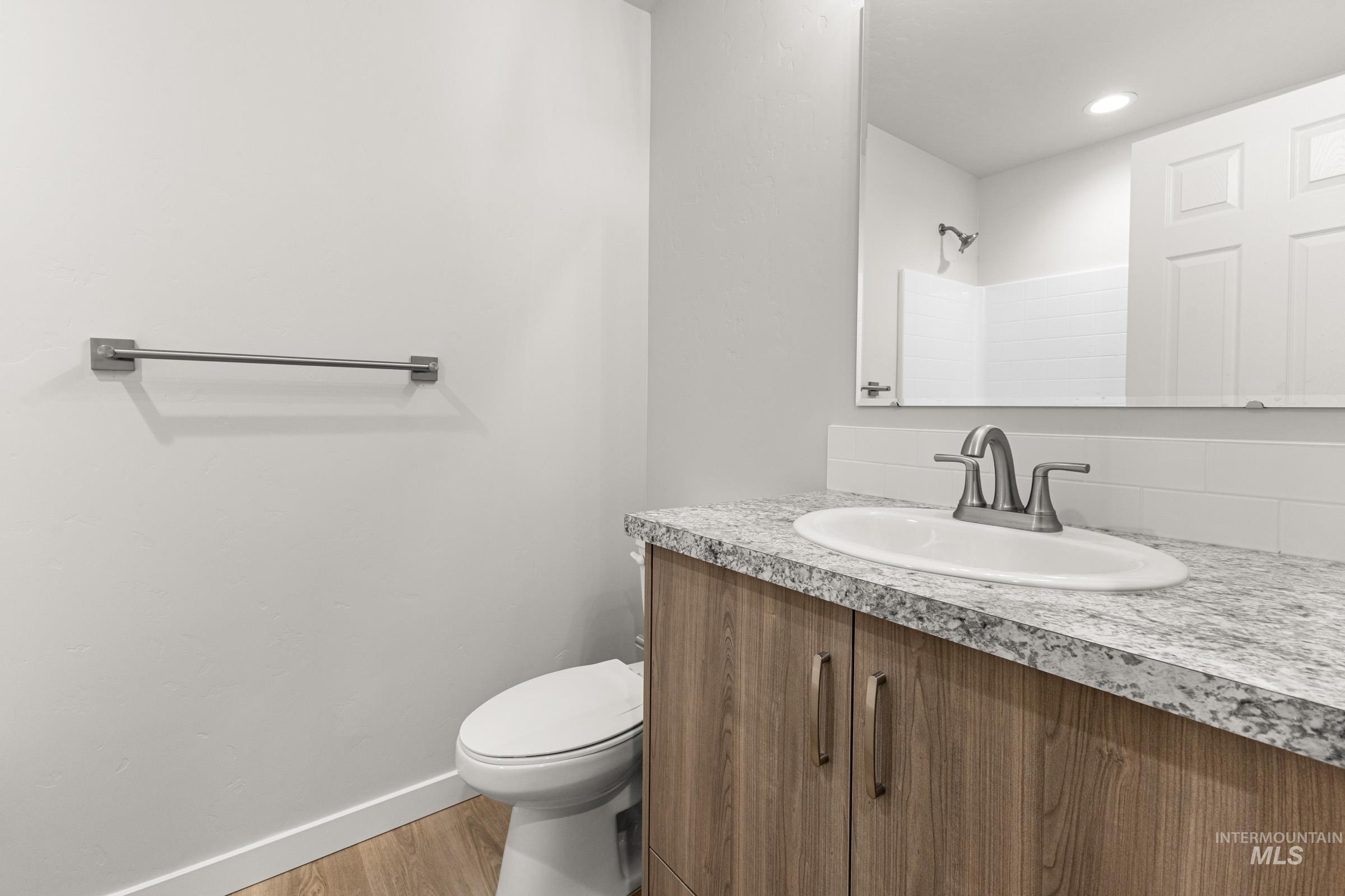 Bathroom vanity with a light wood-finish cabinet and a speckled countertop