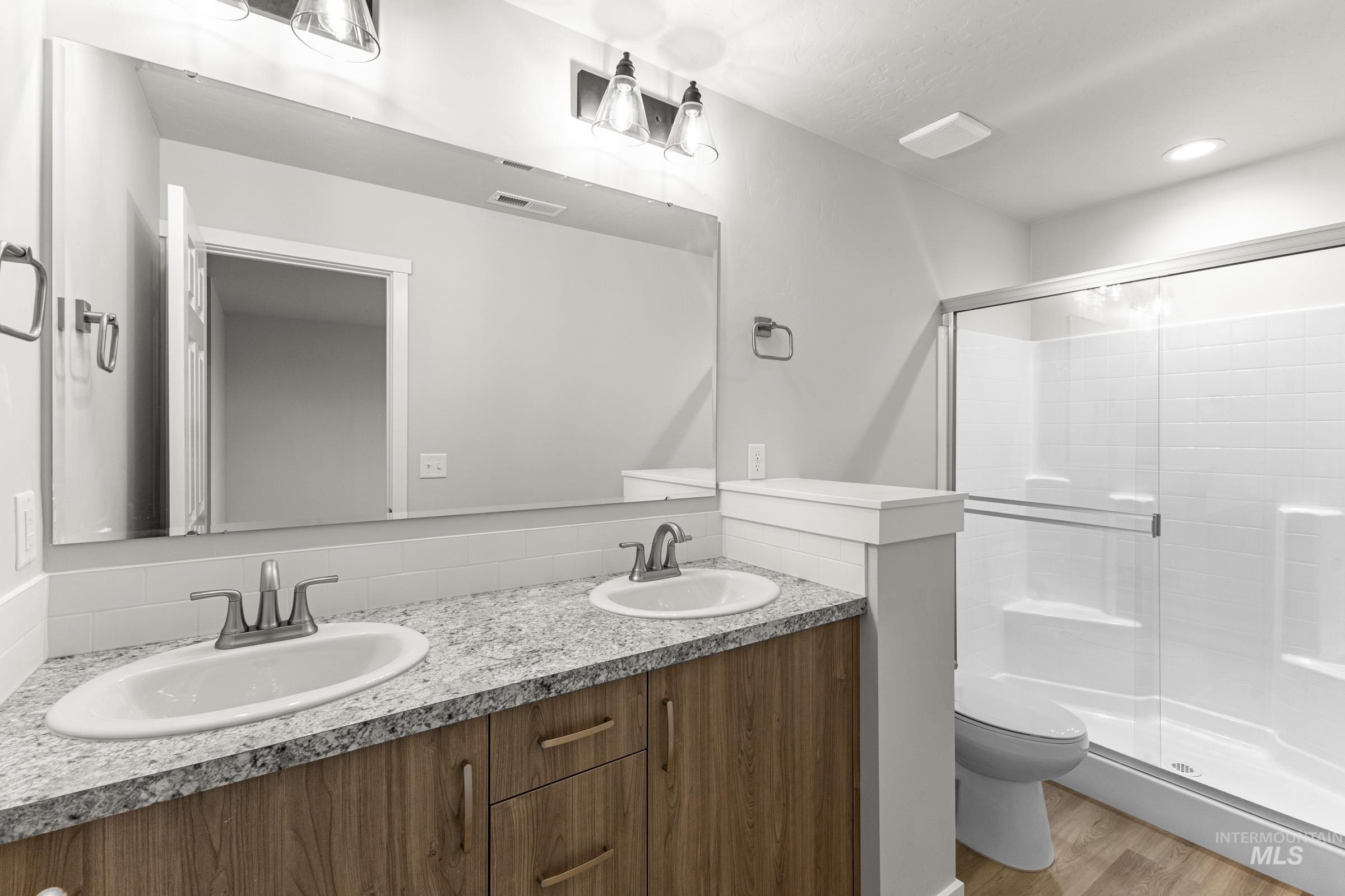 Dual vanity with stone-finish countertop, wood-finish cabinetry, and undermount sinks