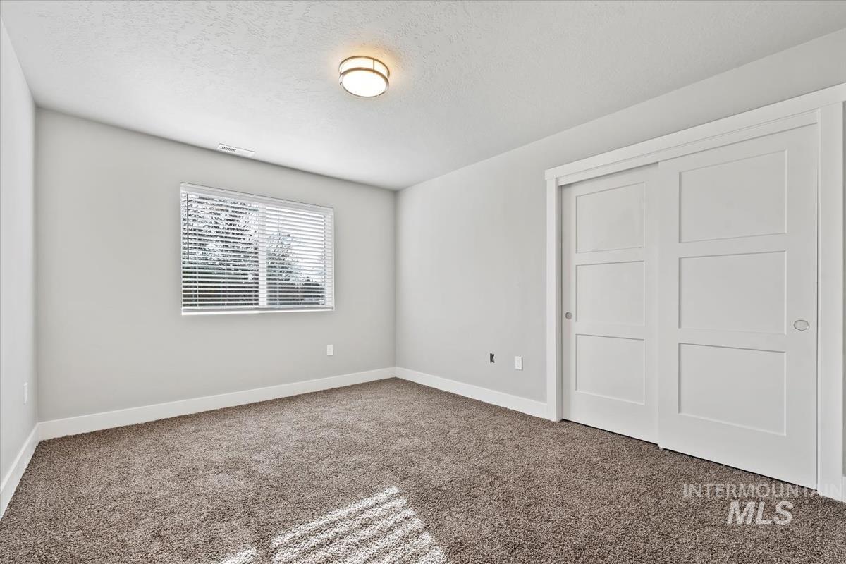 Unfurnished bedroom featuring a textured ceiling, carpet floors, and a closet