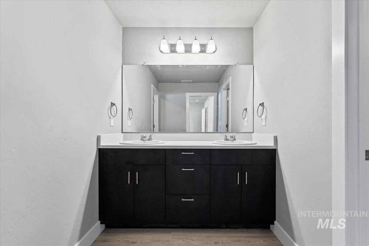 Full bath featuring double vanity and light wood finished floors