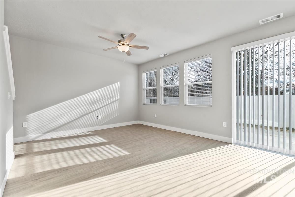 Empty room with ceiling fan and light wood-type flooring