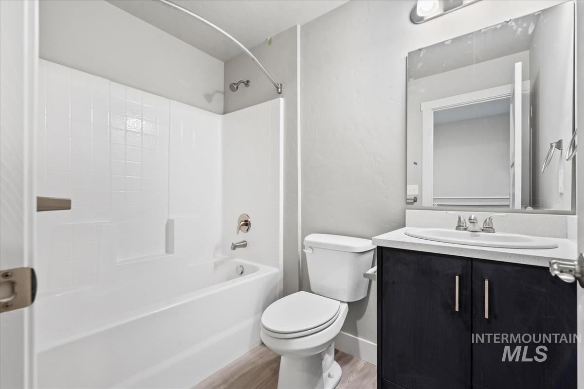 Bathroom with bathing tub / shower combination, vanity, and light wood-type flooring