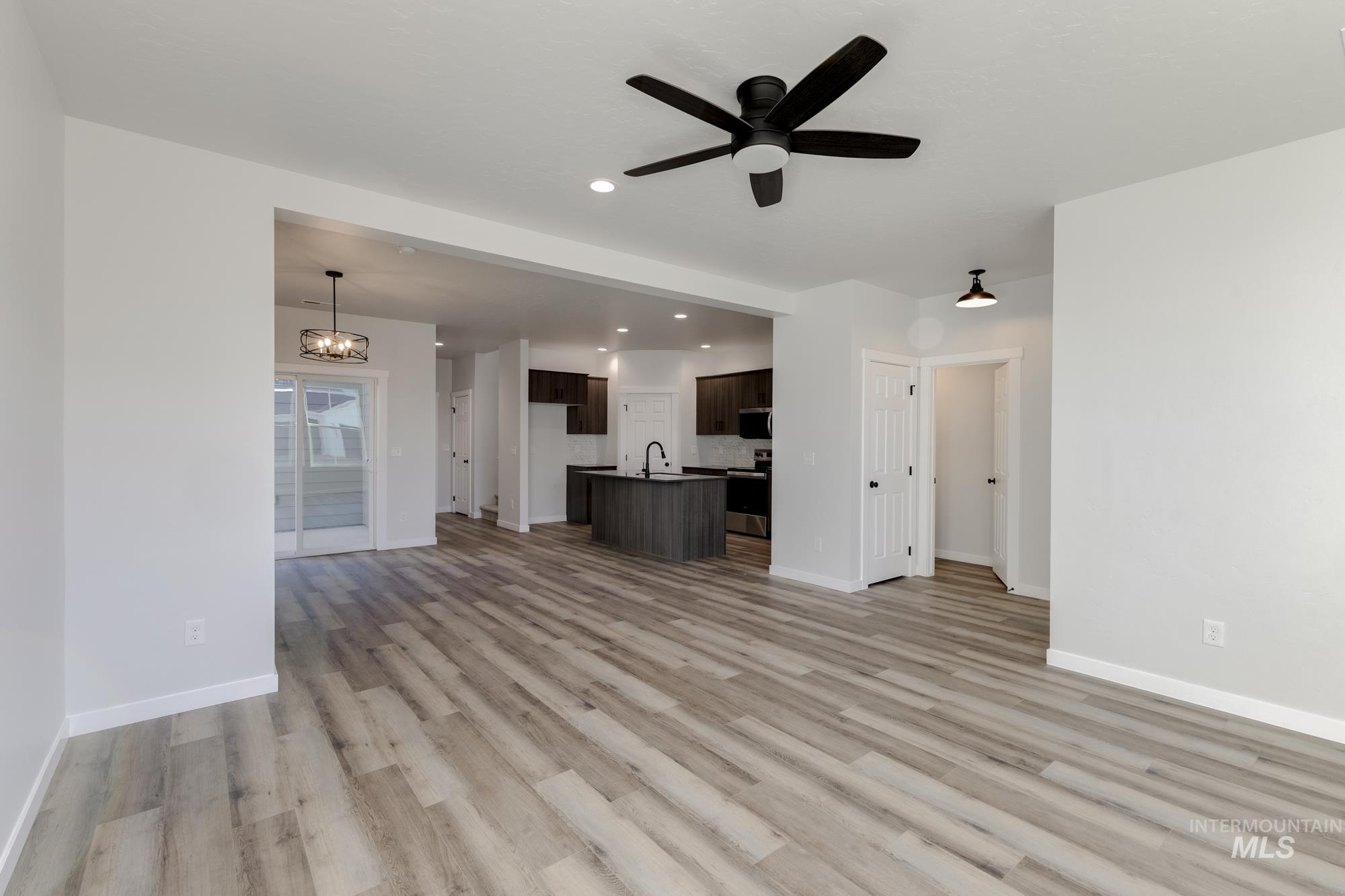 Unfurnished living room with a chandelier, light wood finished floors, recessed lighting, and a ceiling fan