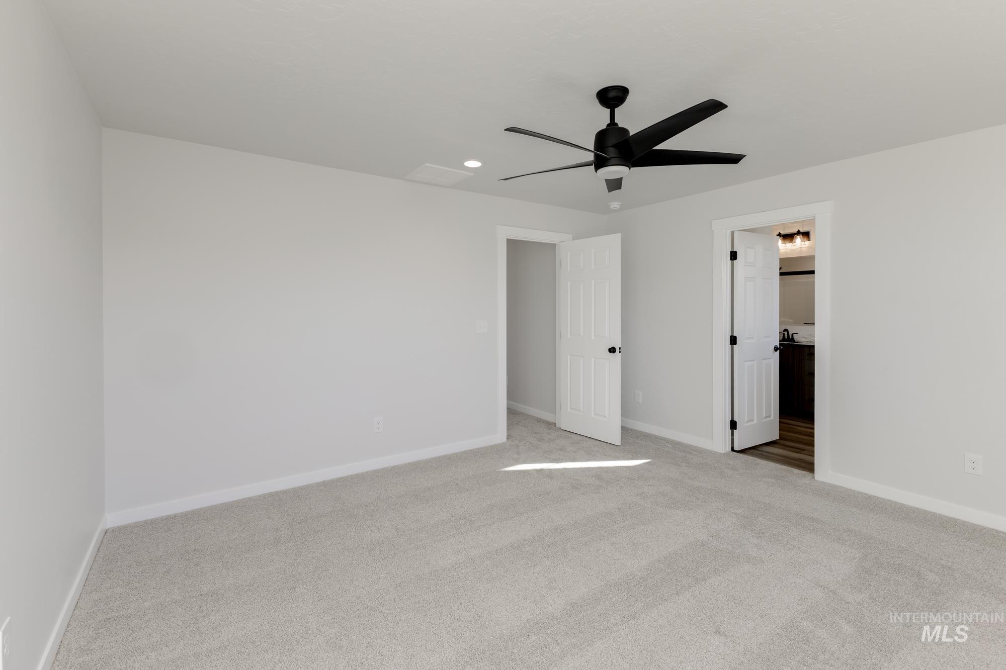 Unfurnished bedroom featuring light carpet, a ceiling fan, ensuite bathroom, and recessed lighting