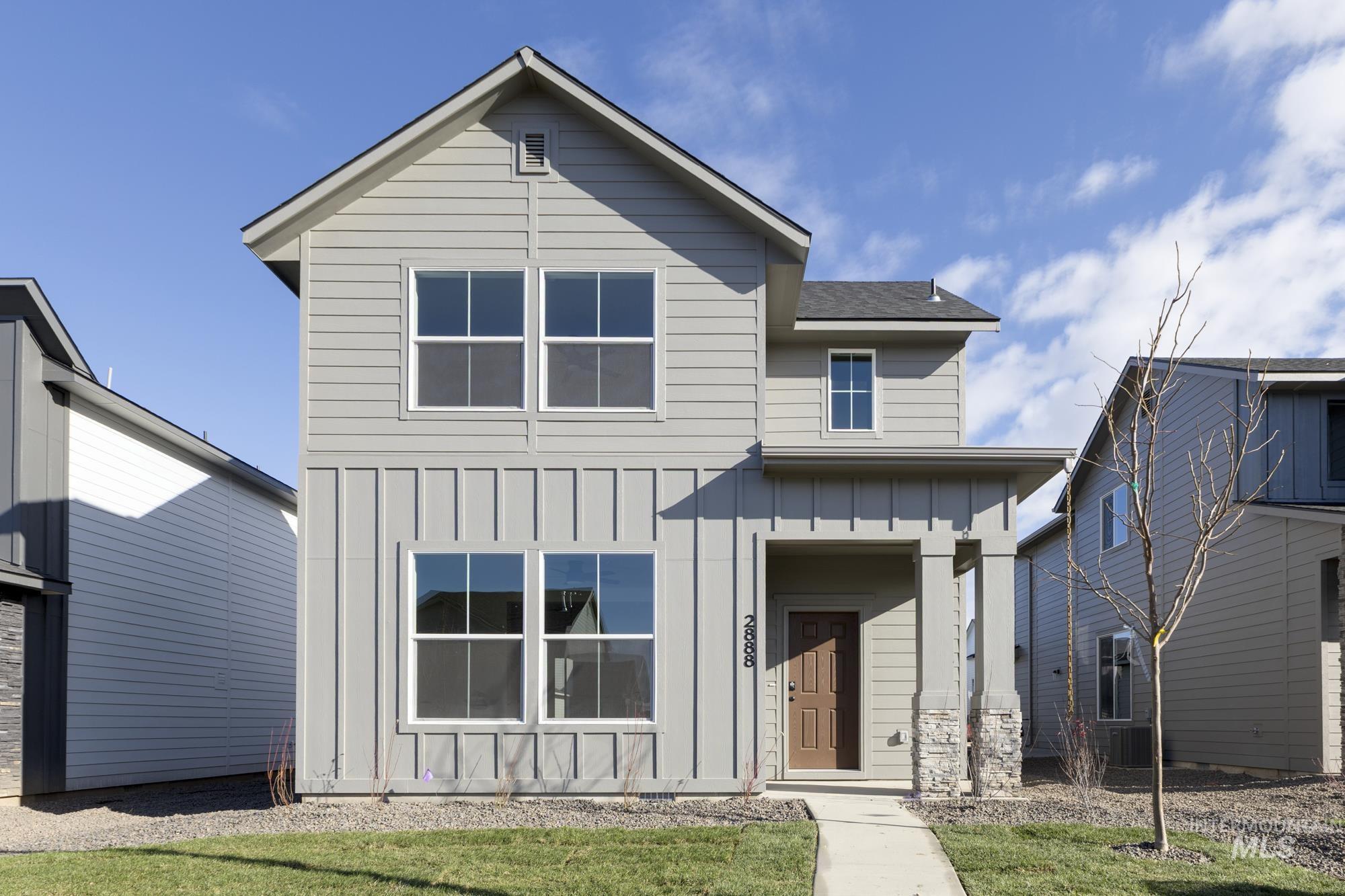 View of front of house featuring board and batten siding, a shingled roof, and a front lawn