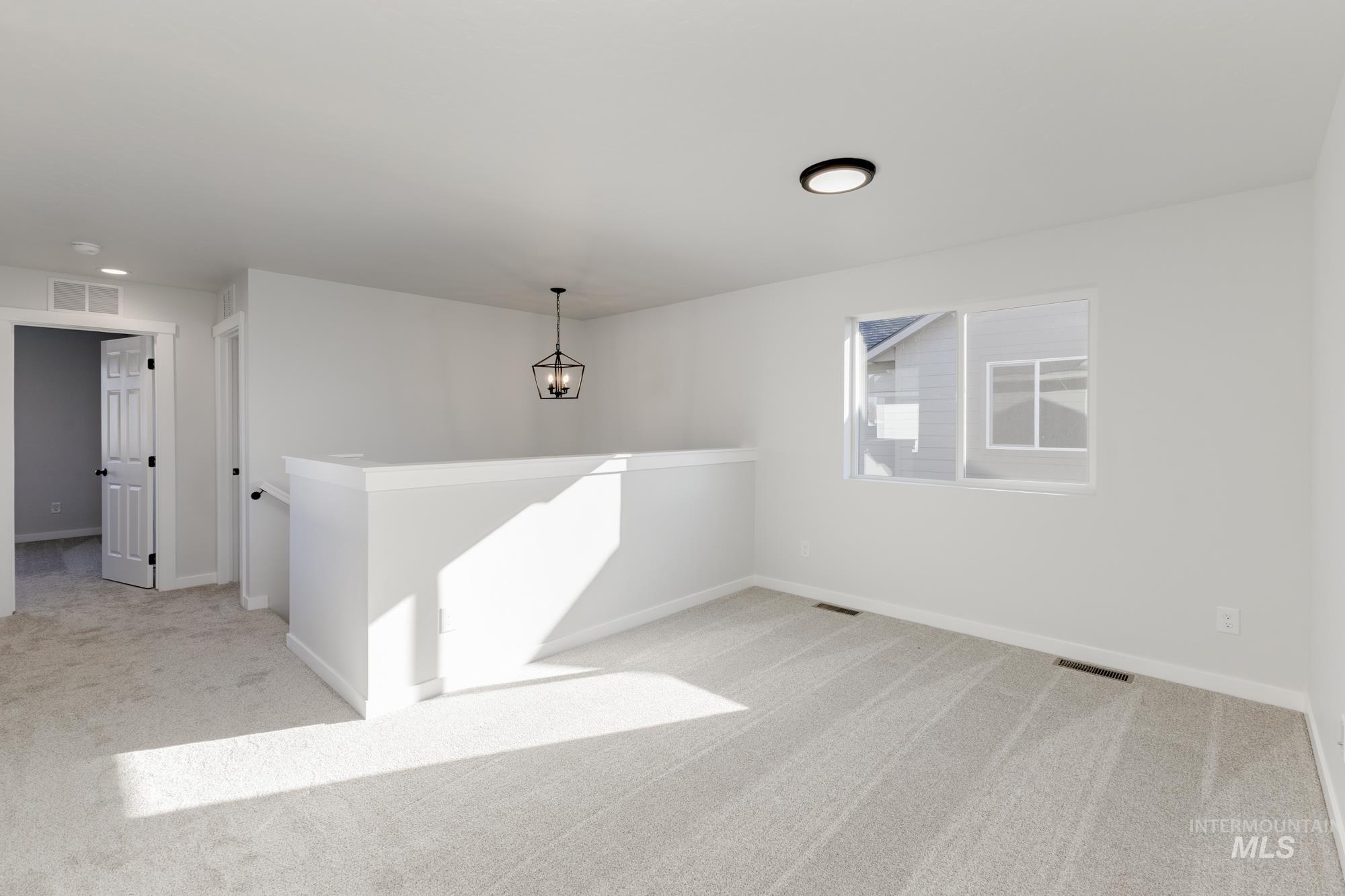 Spare room featuring light colored carpet and baseboards