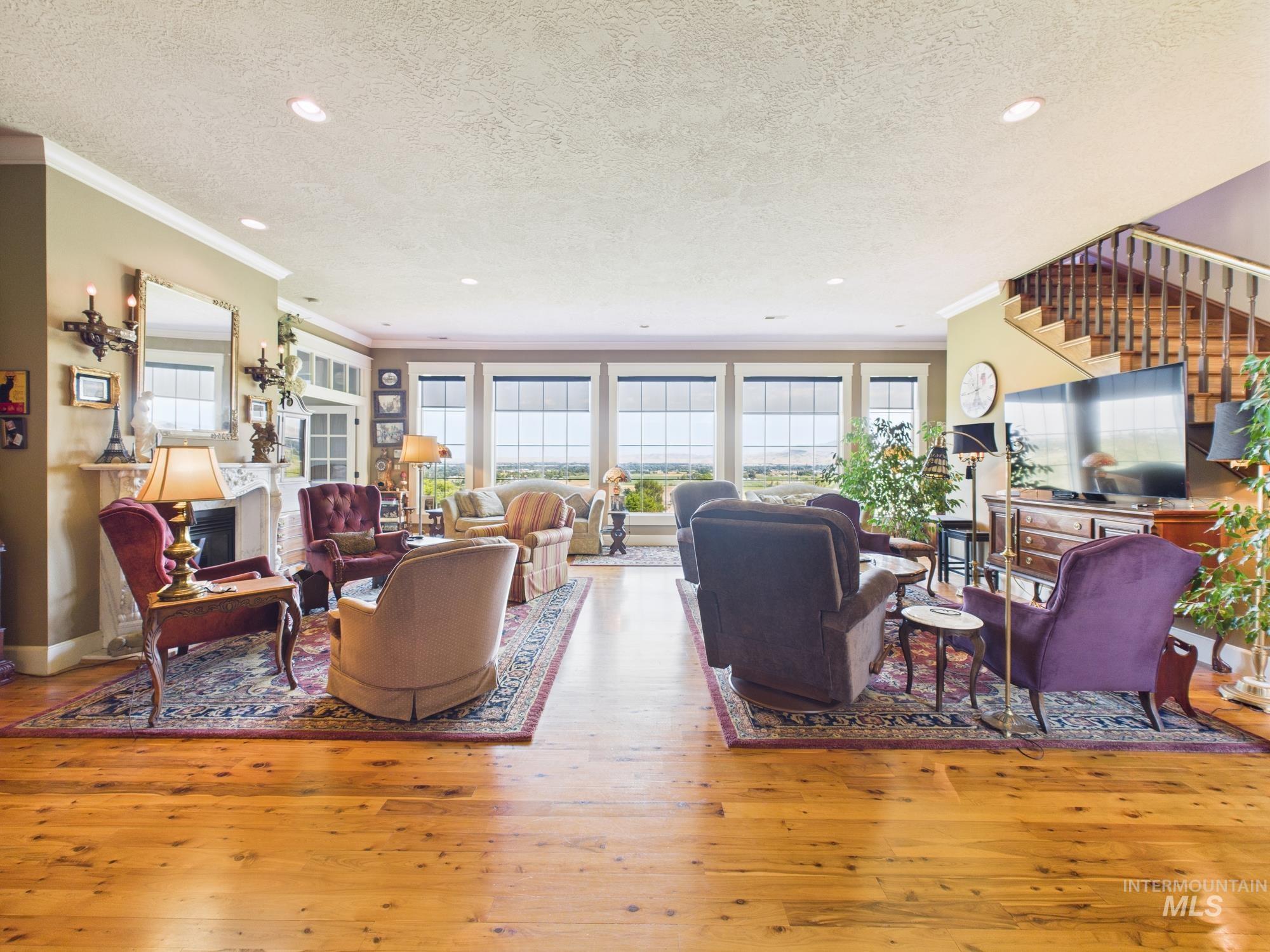 Living area featuring wood-type flooring, crown molding, a textured ceiling, recessed lighting, and stairs