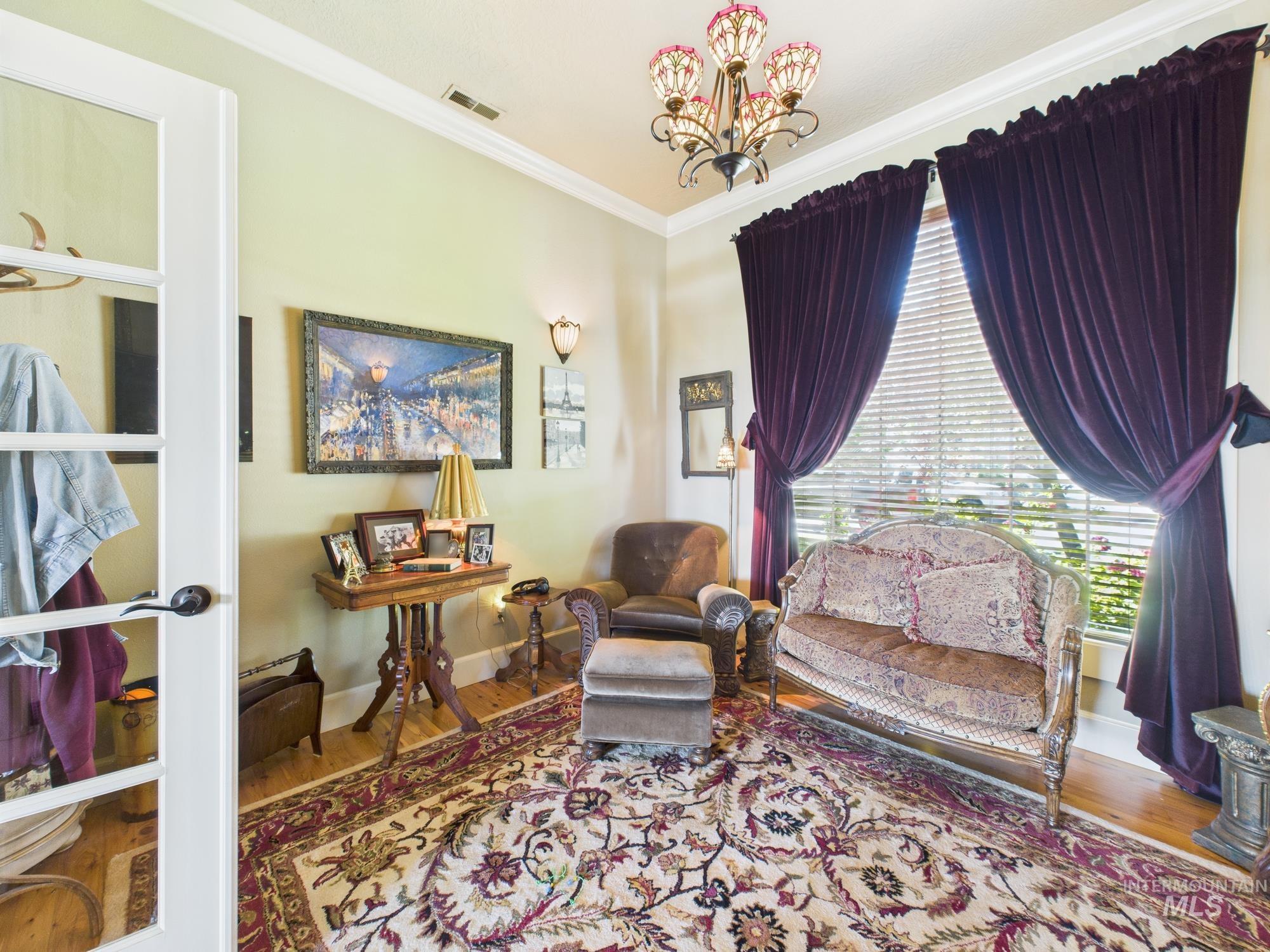 Living area featuring crown molding, wood finished floors, and a chandelier