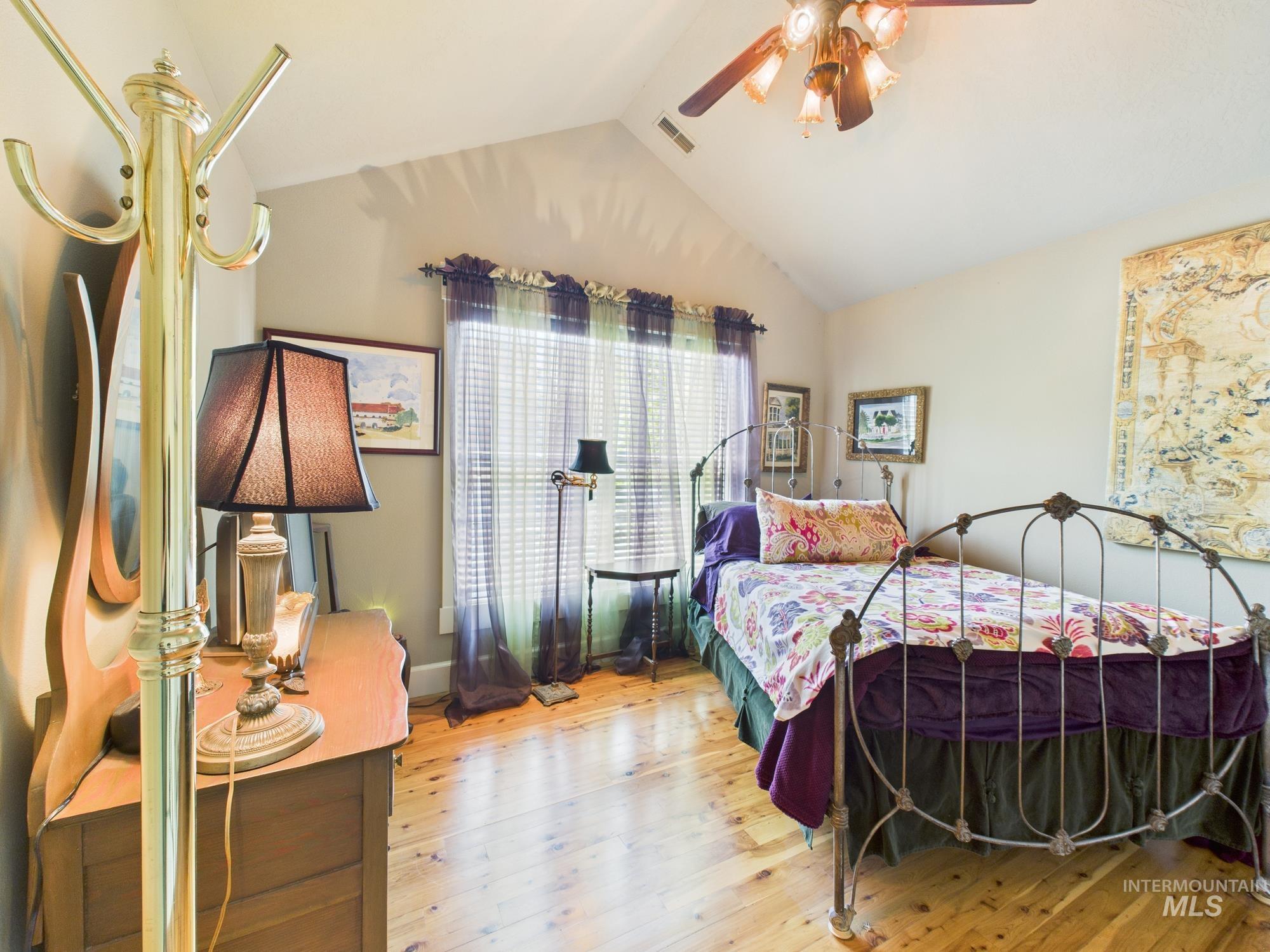 Bedroom featuring vaulted ceiling, wood finished floors, and ceiling fan