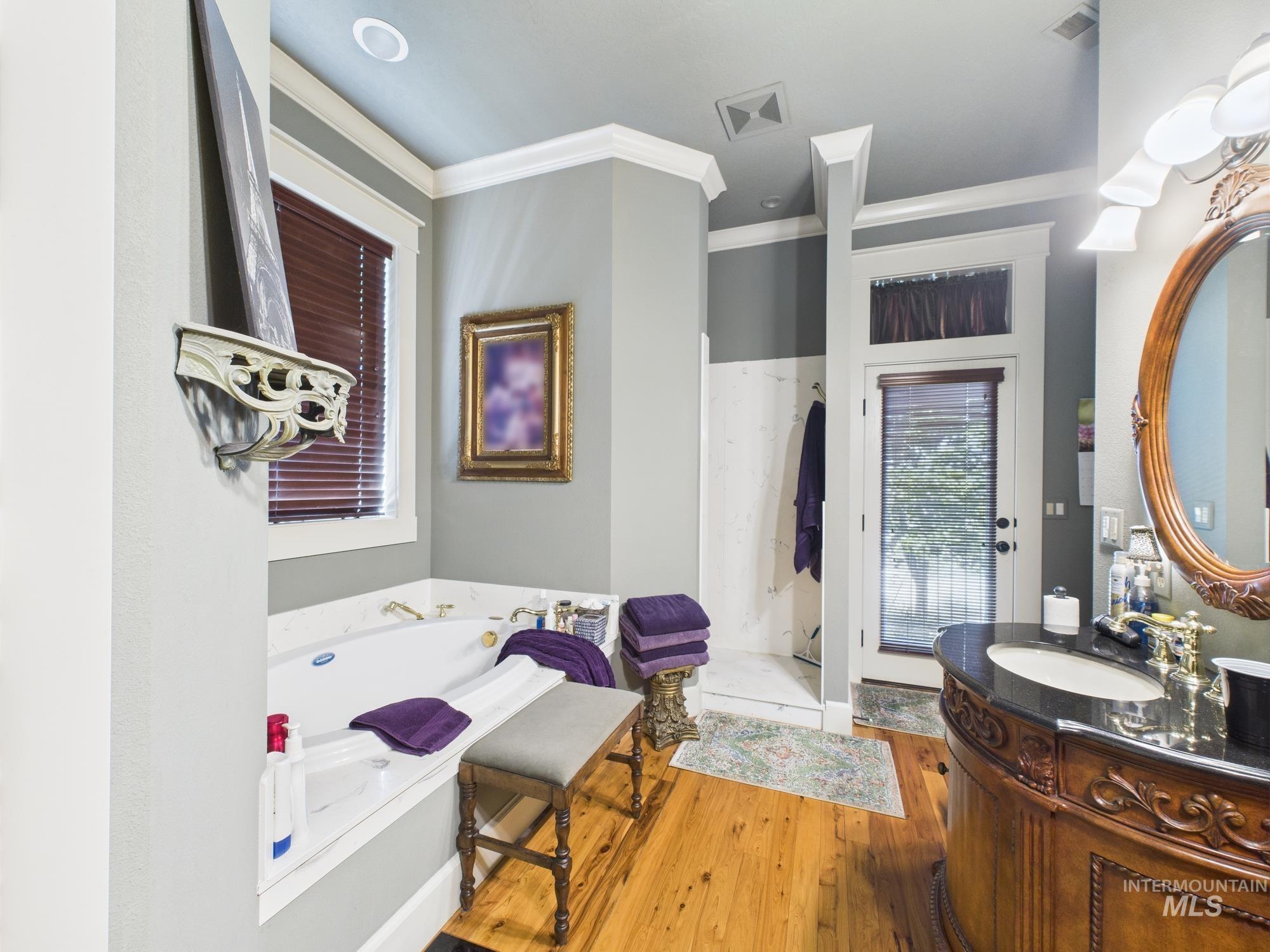 Full bath with crown molding, wood-type flooring, vanity, and a bath
