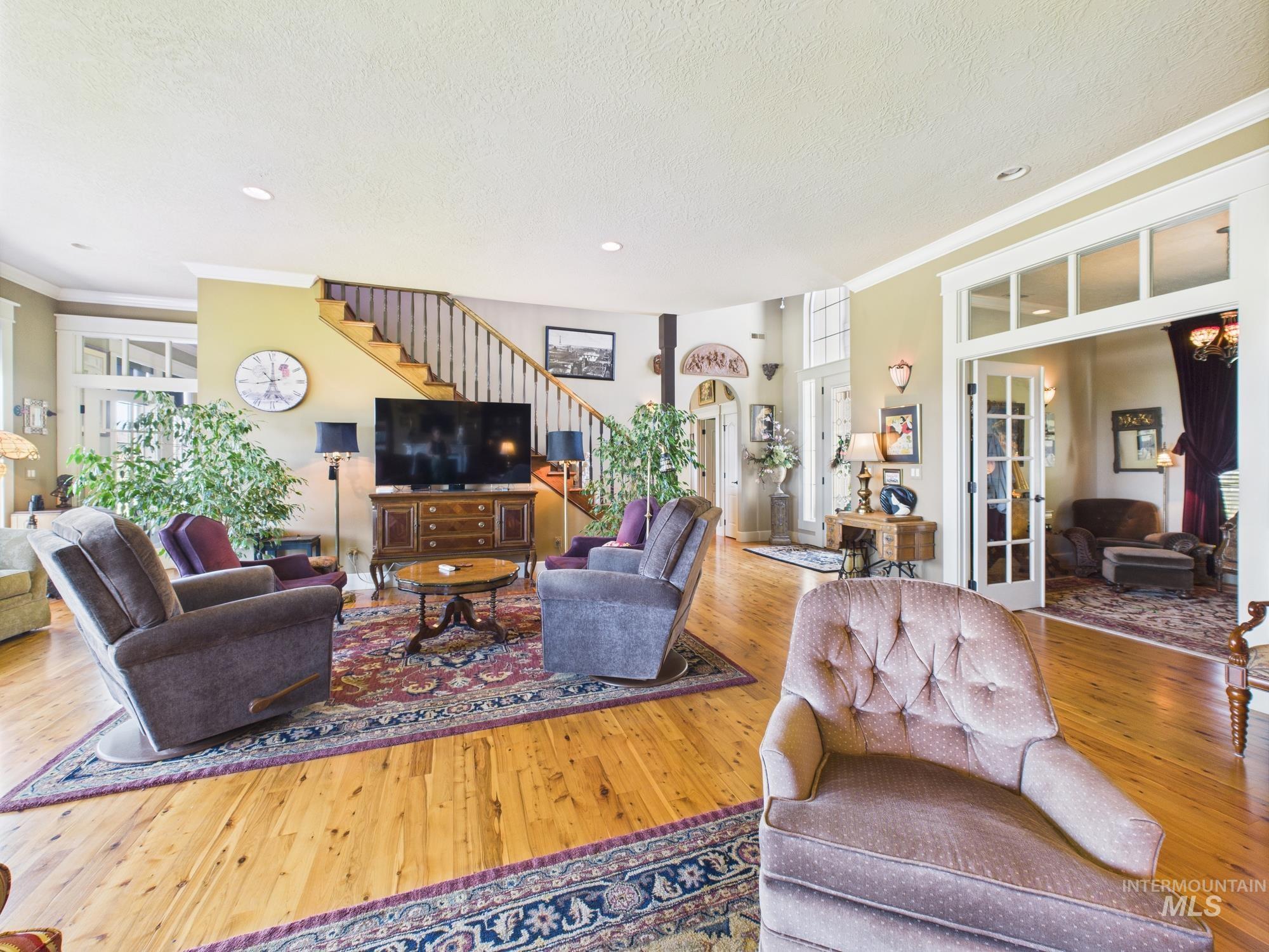 Living room with hardwood / wood-style flooring, stairs, ornamental molding, healthy amount of natural light, and a textured ceiling