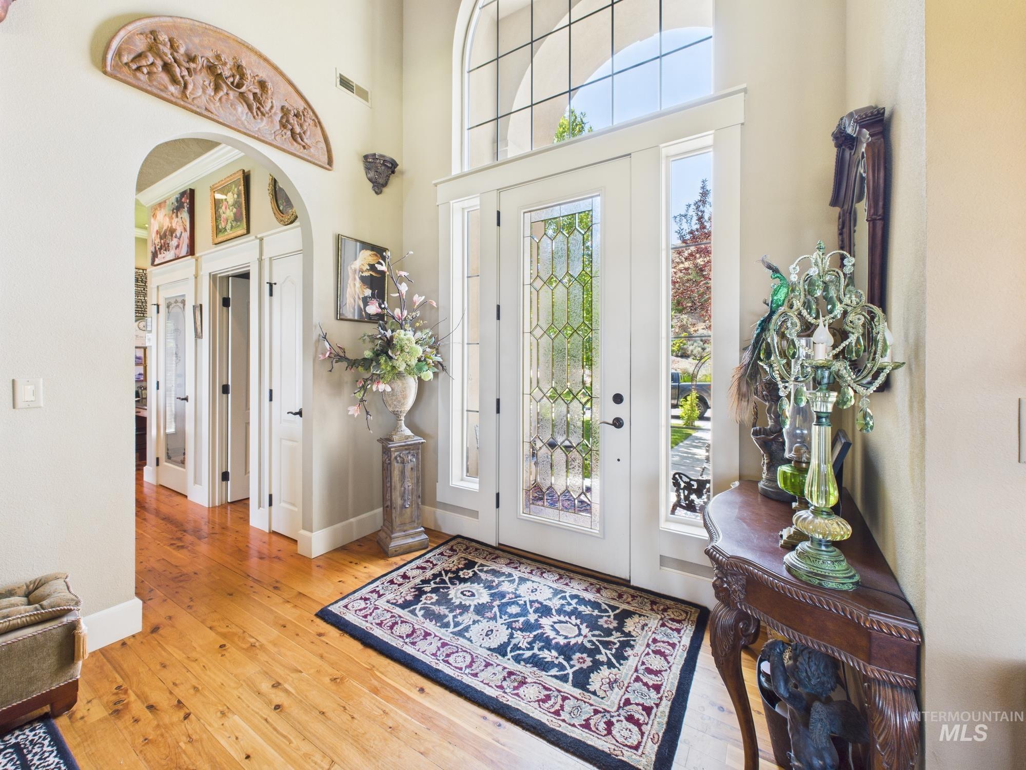 Foyer entrance featuring arched walkways, wood-type flooring, and a towering ceiling