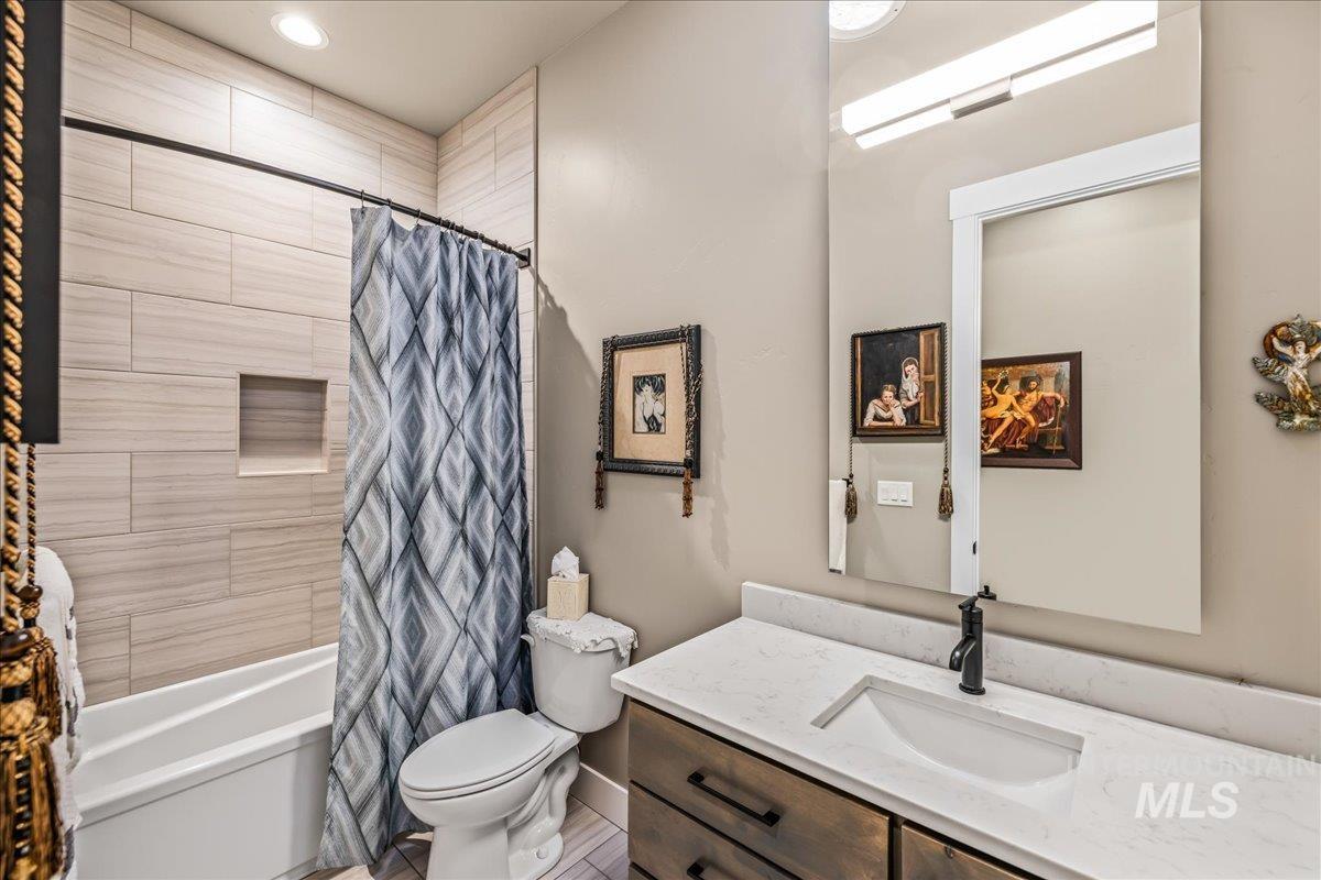 Bathroom featuring vanity, shower / tub combo with curtain, and recessed lighting