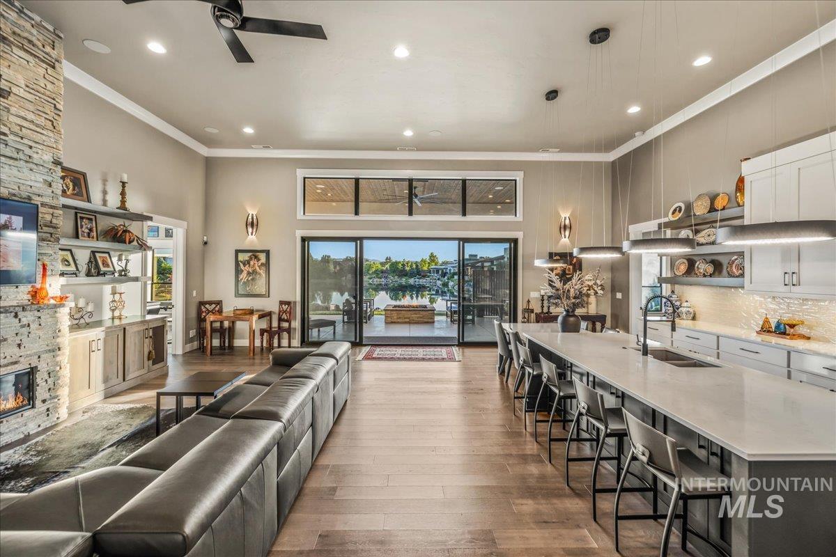 Living area featuring ceiling fan, crown molding, wood-type flooring, a fireplace, and recessed lighting
