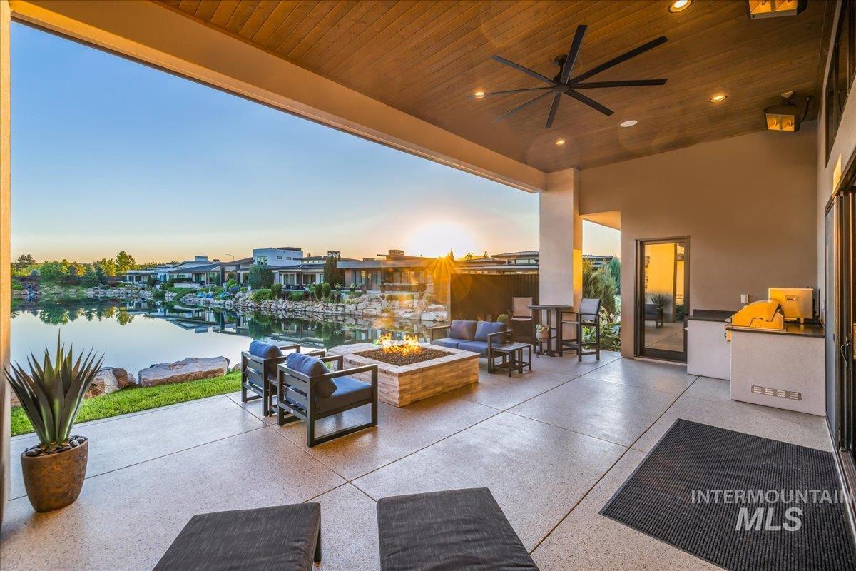 View of patio / terrace with a water view, exterior kitchen, ceiling fan, and an outdoor living space with a fire pit