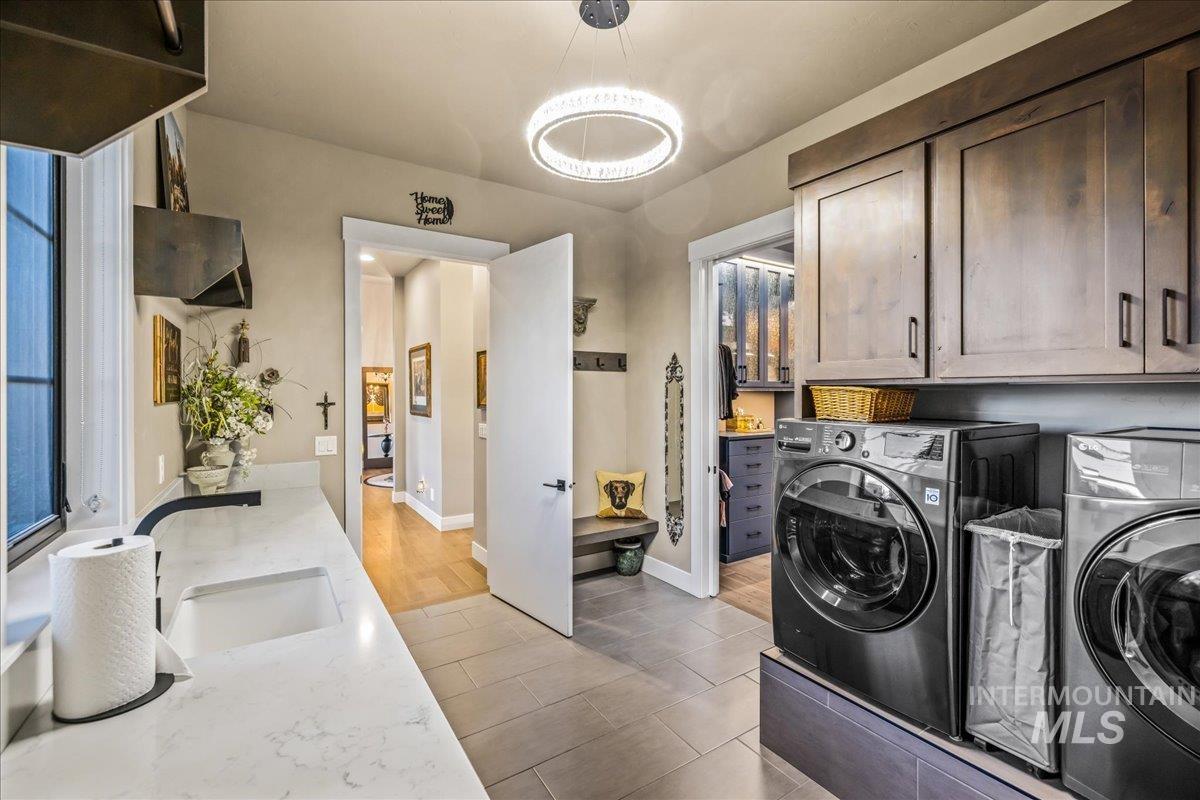 Washroom featuring independent washer and dryer, cabinet space, and a chandelier