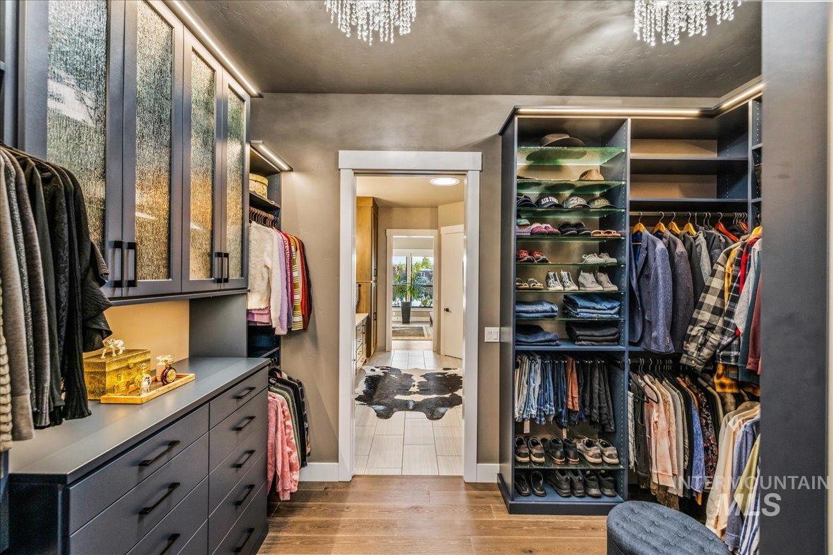Walk in closet featuring wood finished floors and a chandelier