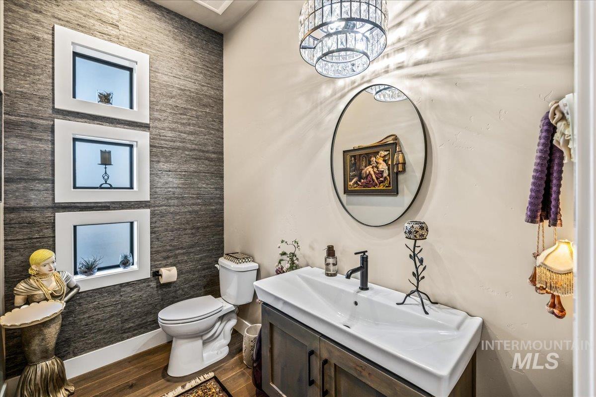 Half bath with vanity, wood finished floors, and a chandelier