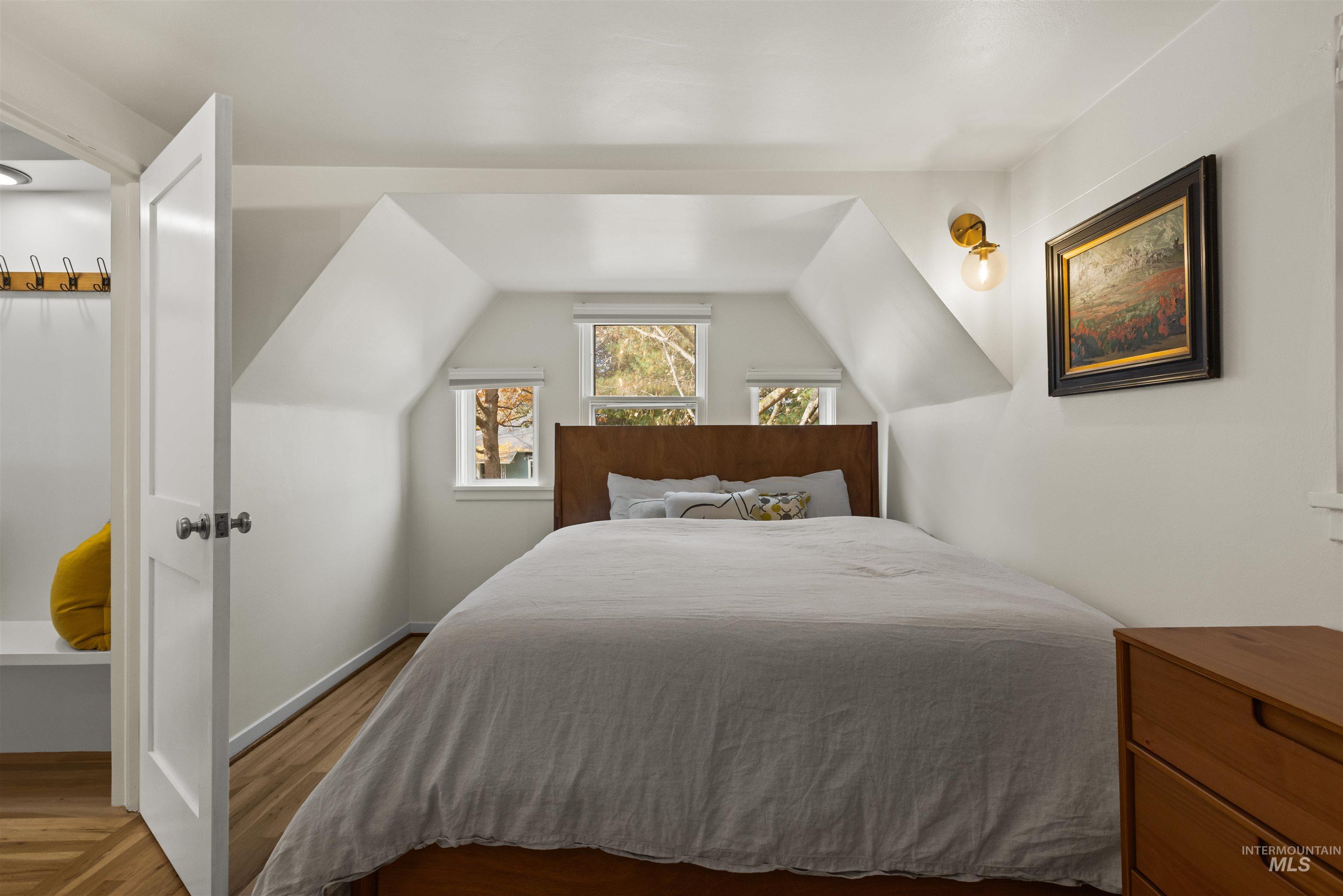 Bedroom featuring wood finished floors and vaulted ceiling