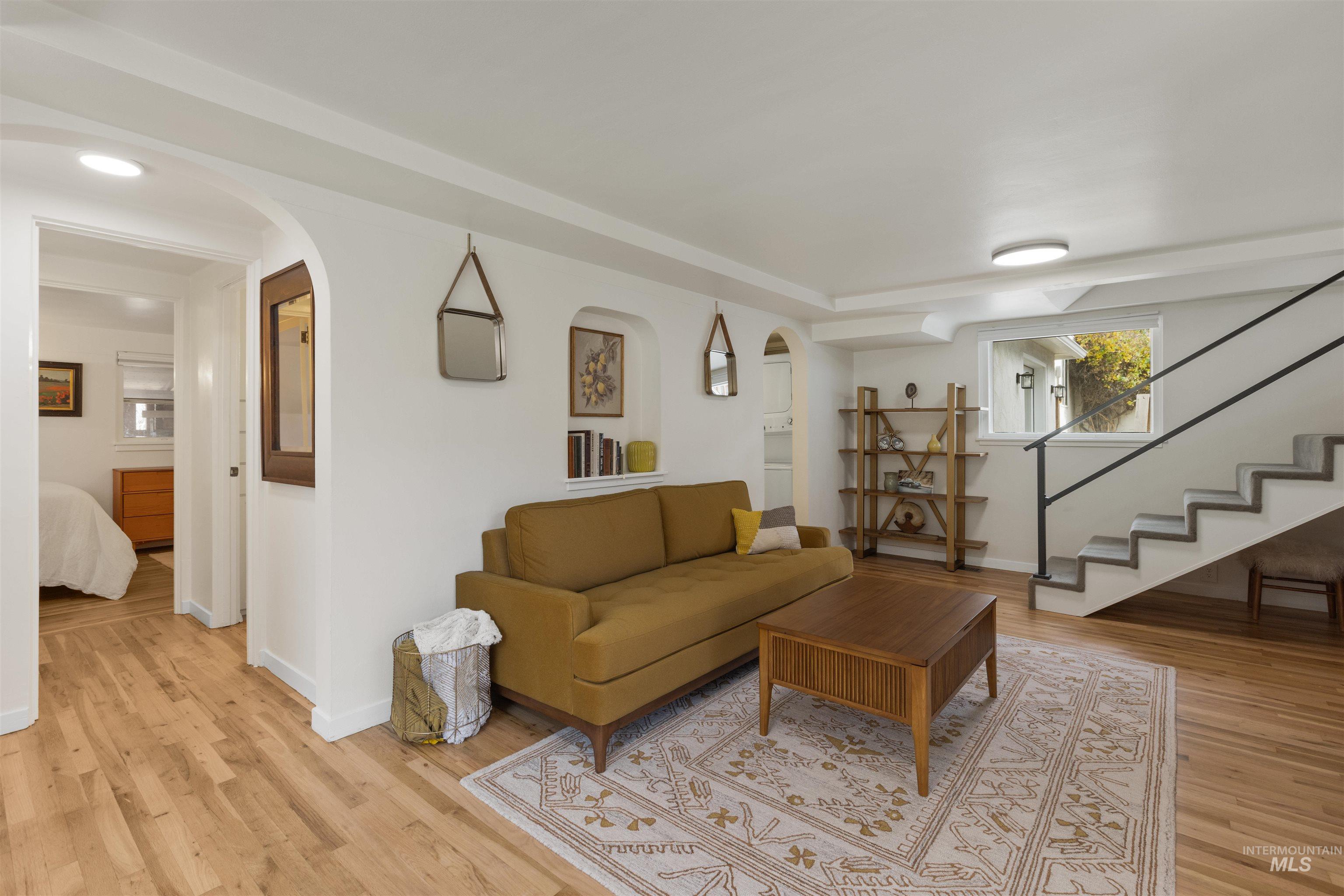 Living room featuring stairway, arched walkways, and light wood finished floors