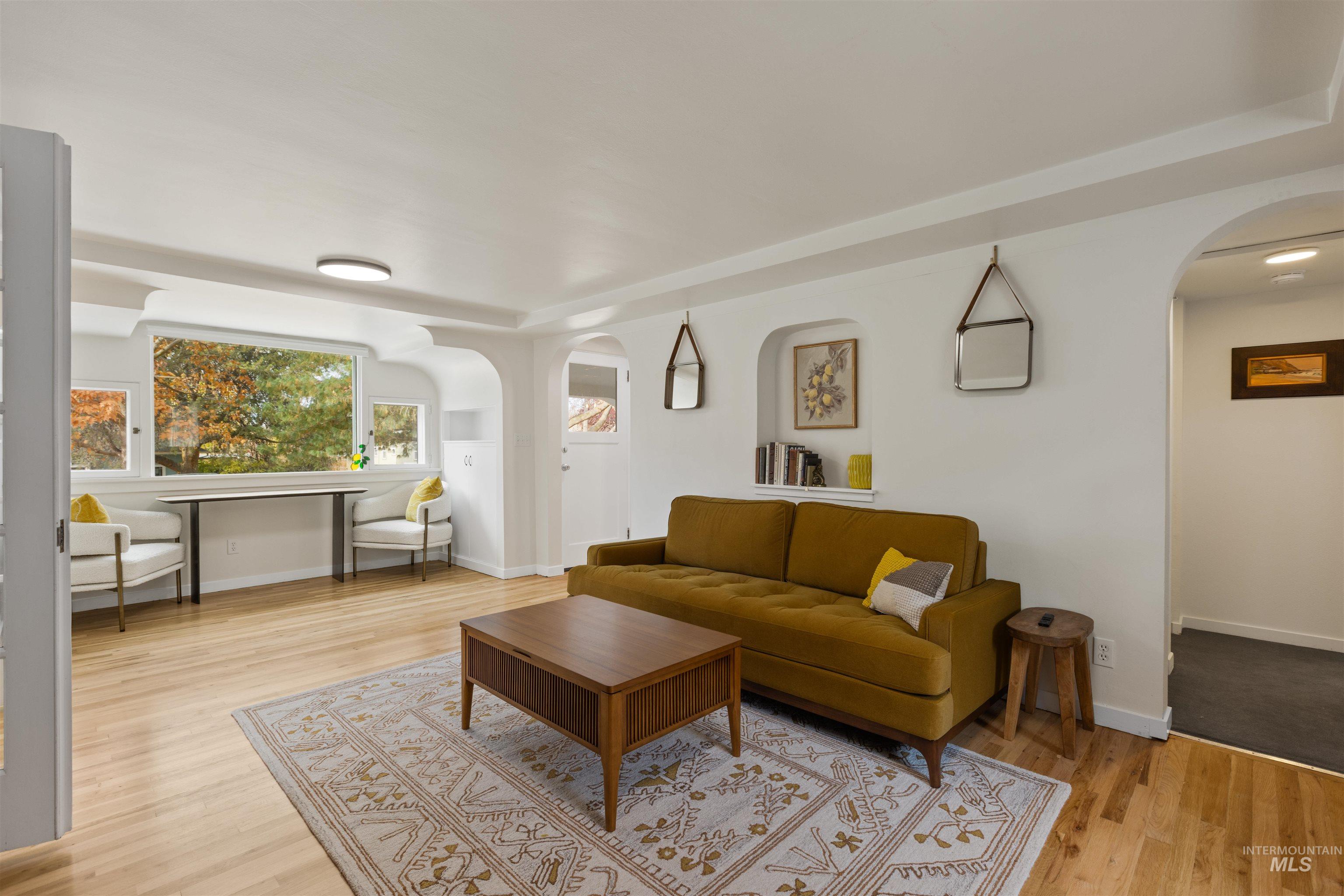 Living room featuring arched walkways and light wood-style flooring