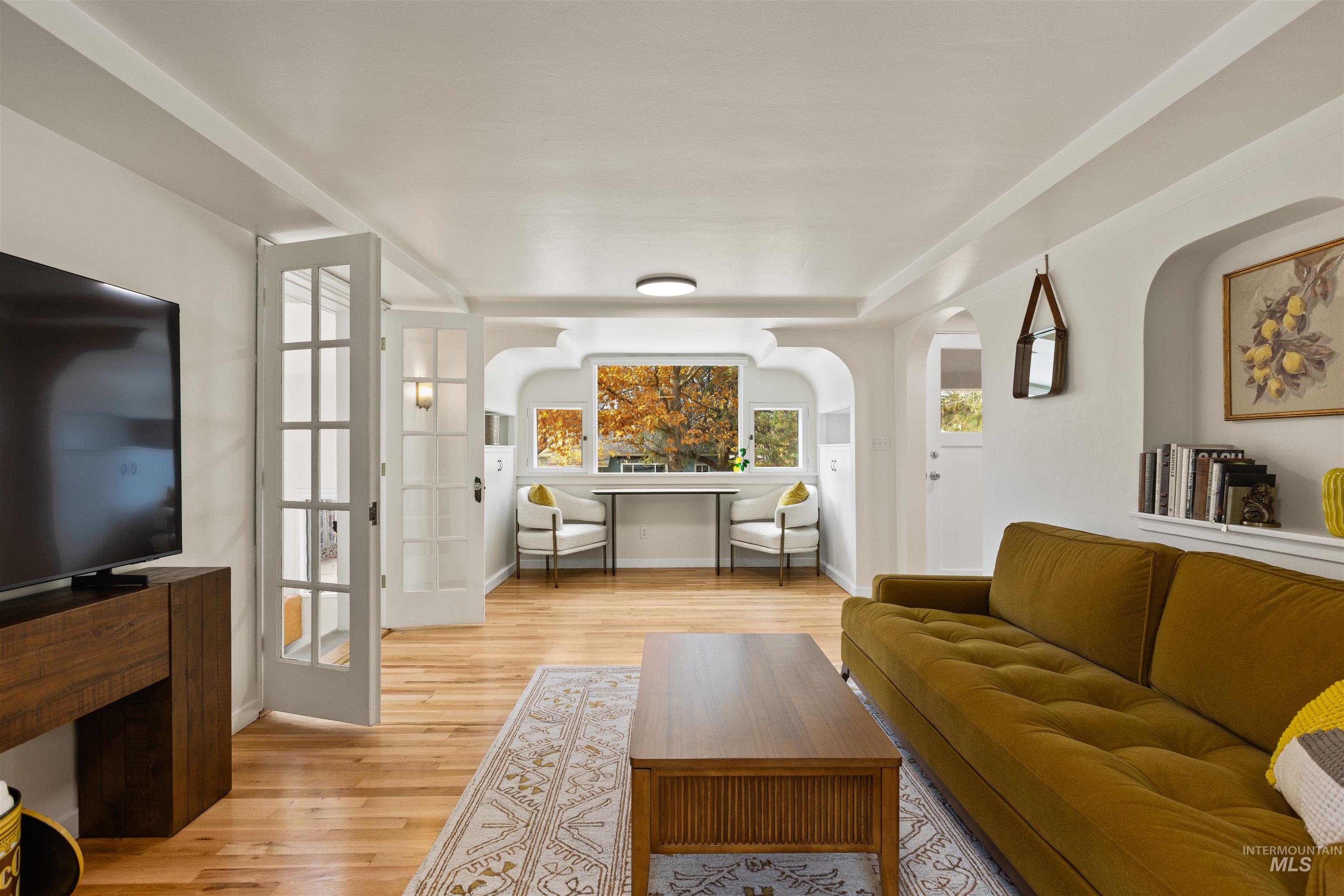 Living room featuring light wood-type flooring and arched walkways