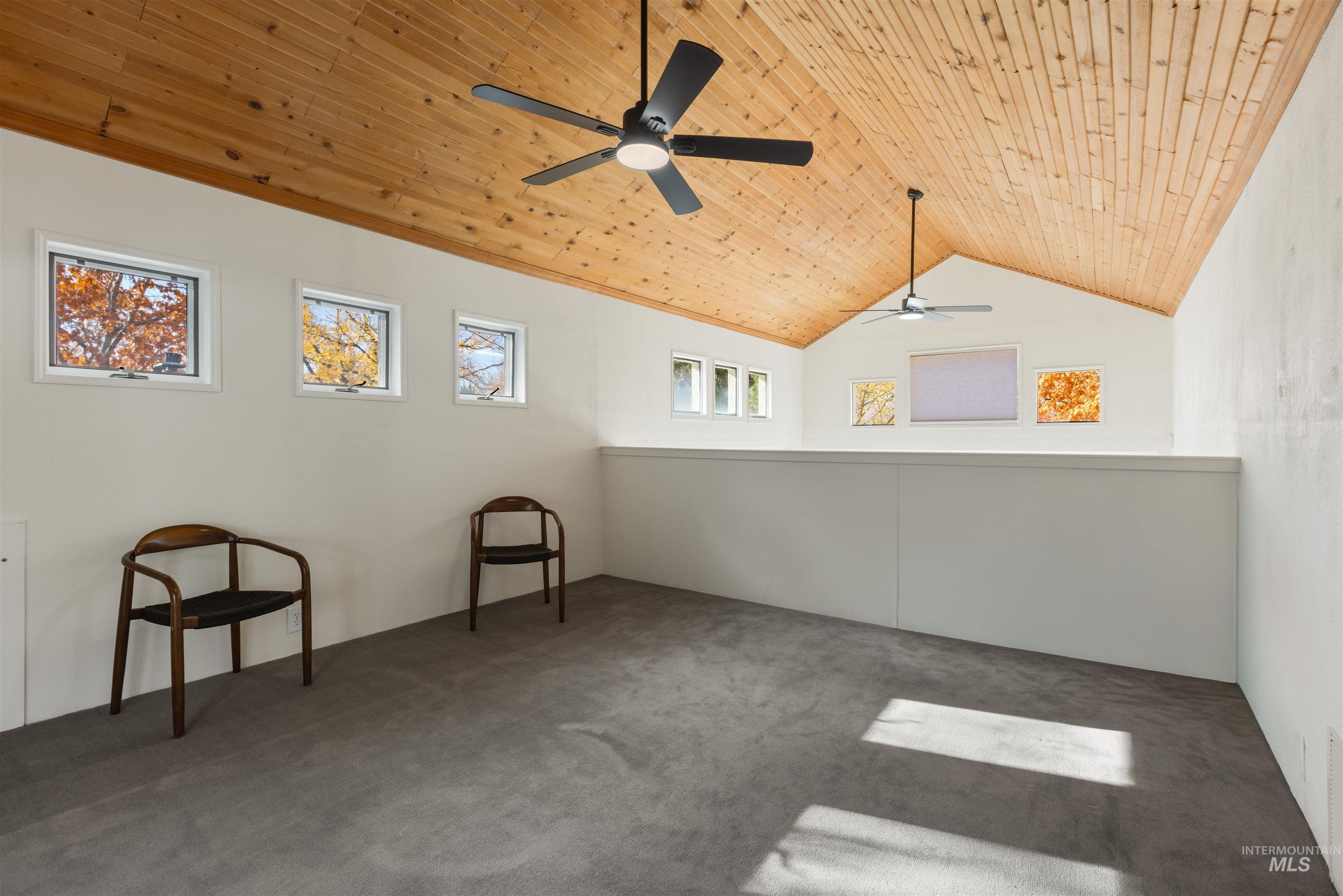 Carpeted spare room with wood ceiling, lofted ceiling, and ceiling fan