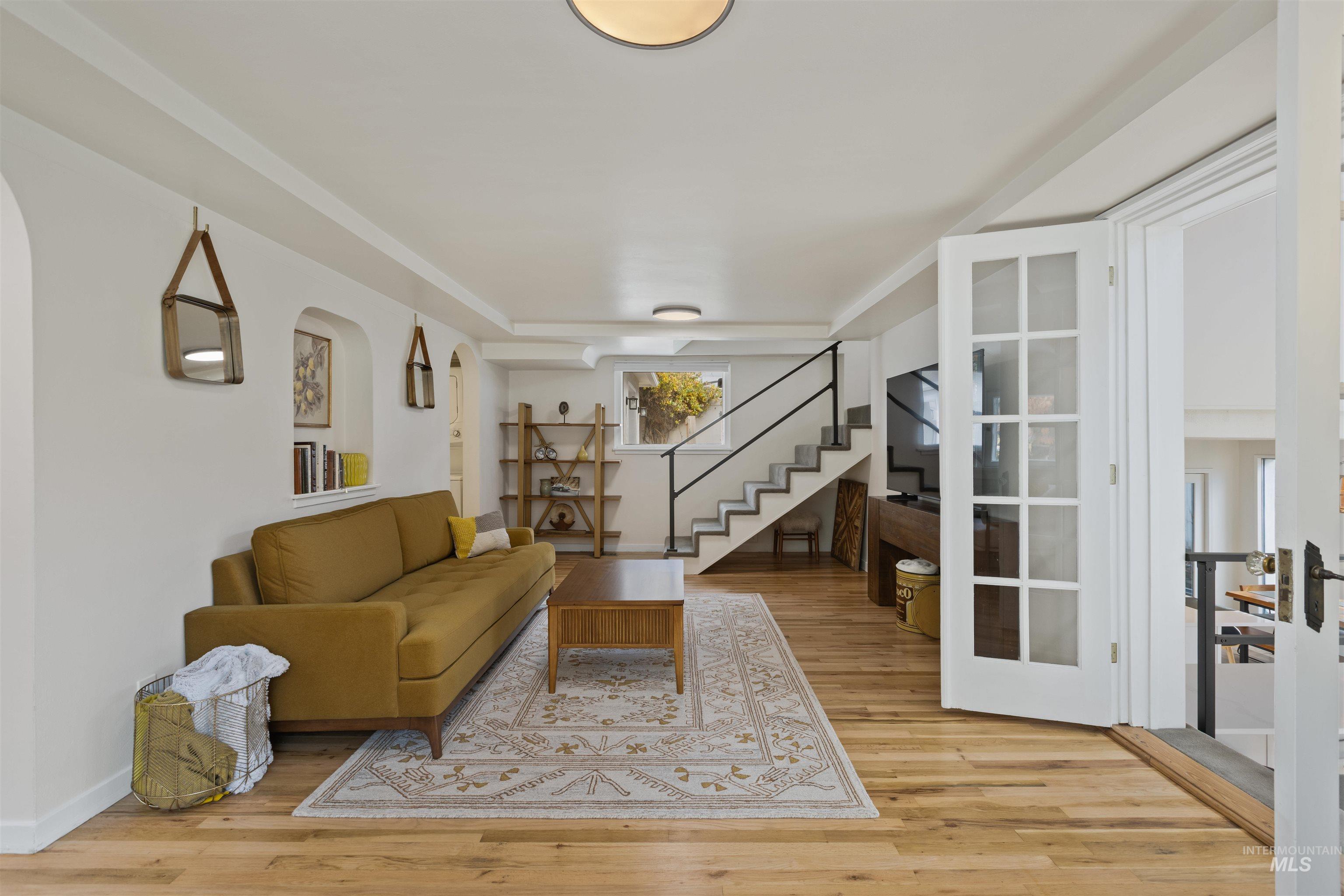 Living room featuring light wood finished floors, stairs, and french doors