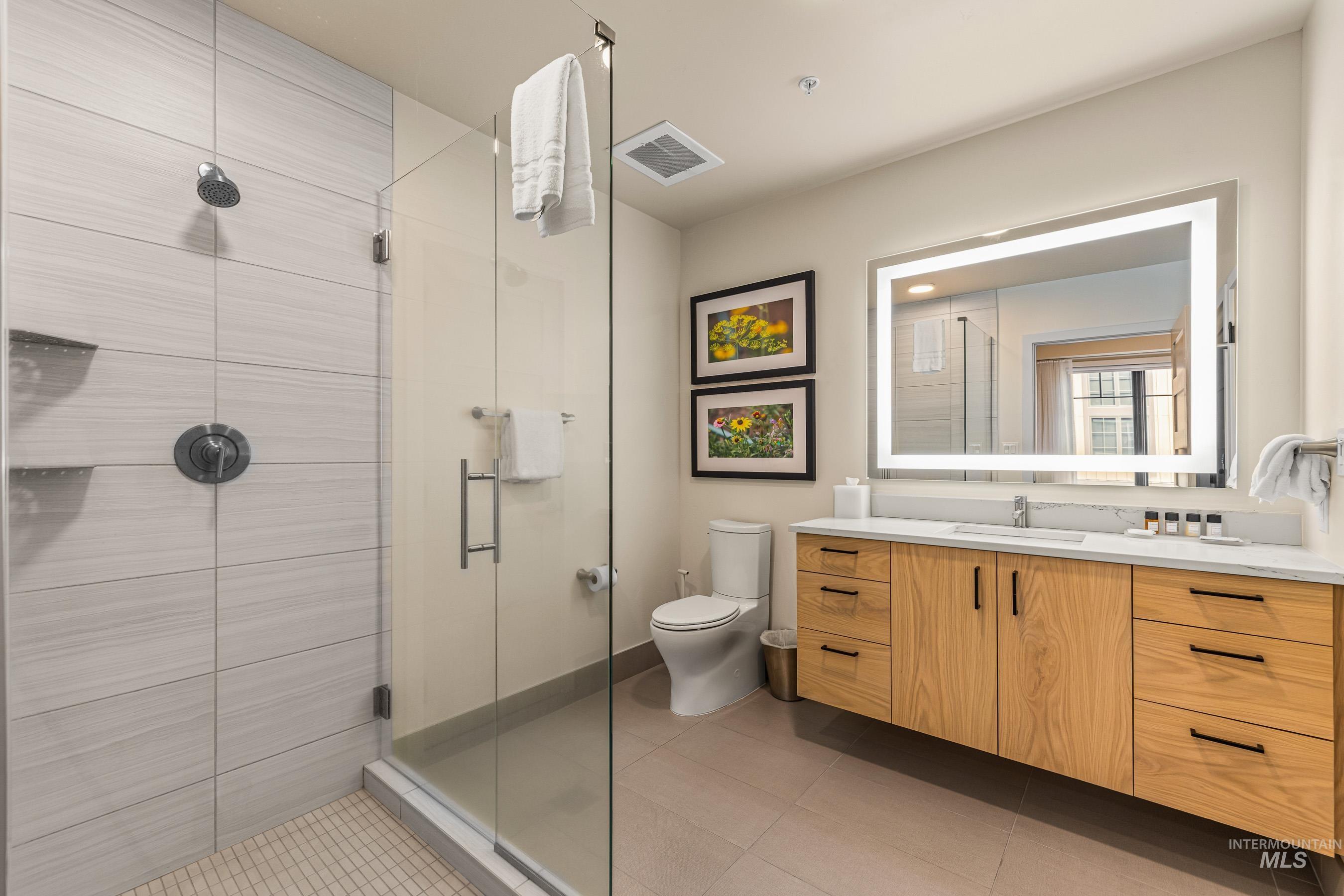 Full bath with a shower stall, vanity, and light tile patterned flooring