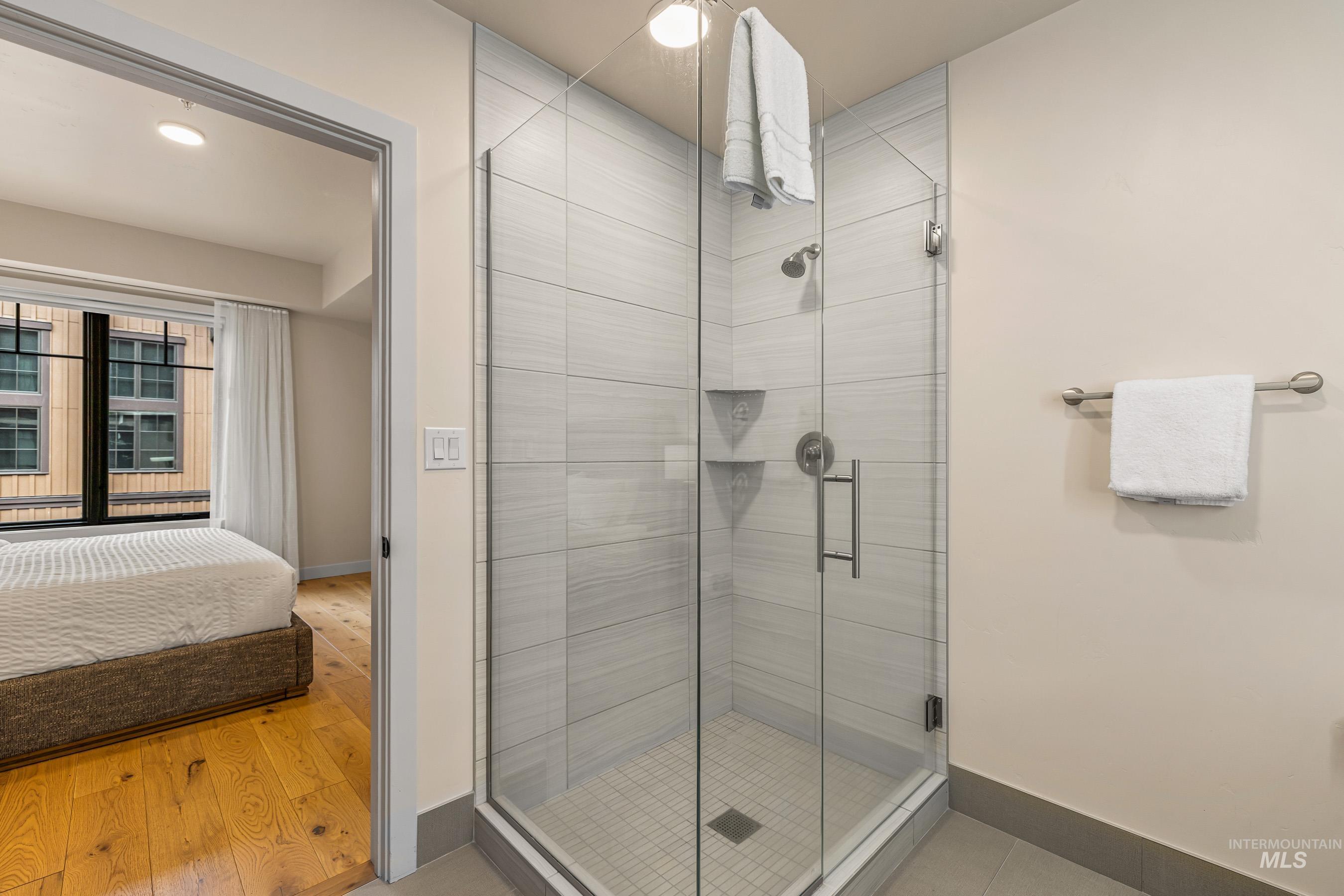 Ensuite bathroom featuring a stall shower and light wood-type flooring