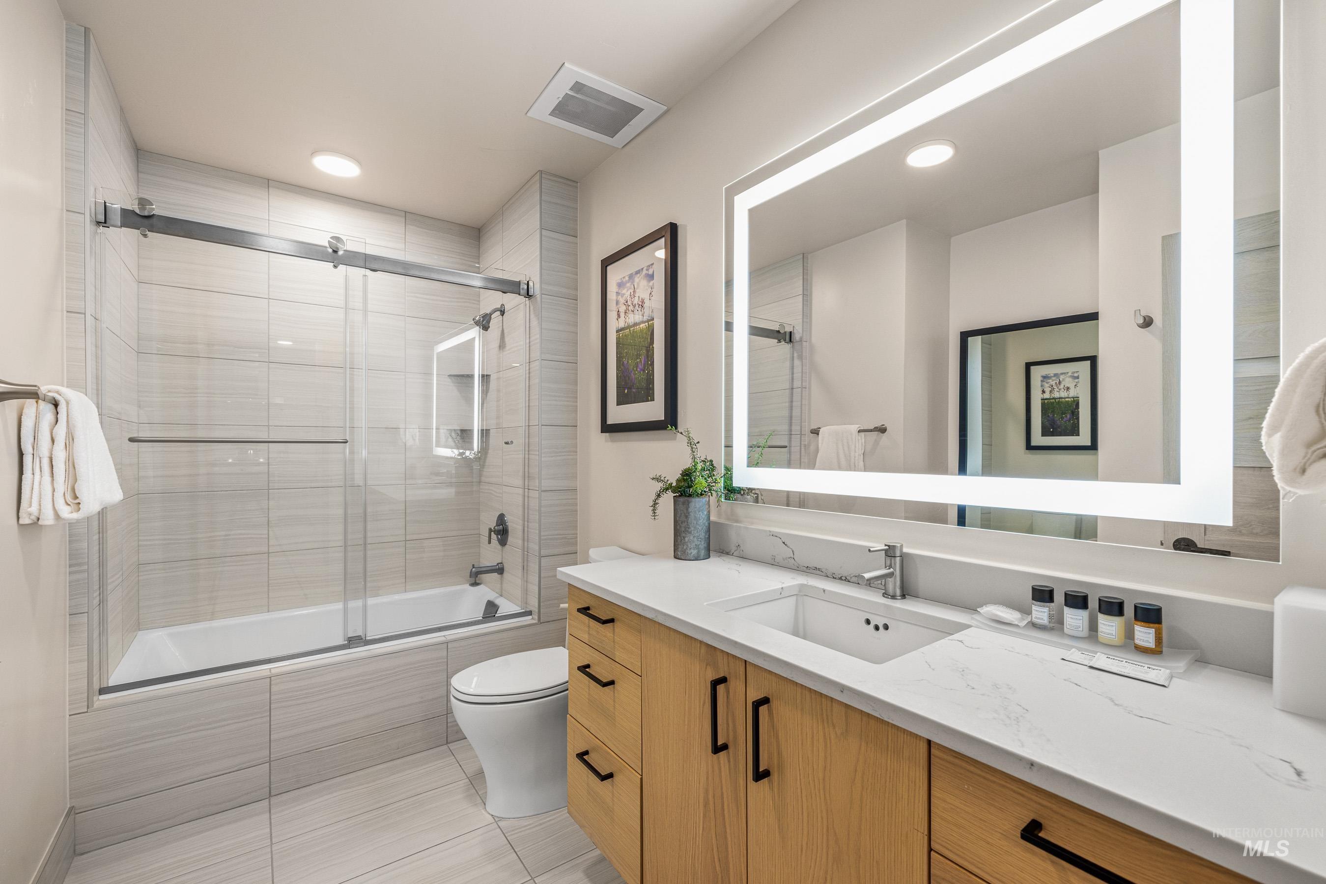 Bathroom with tiled shower / bath combo, vanity, recessed lighting, and light tile patterned floors