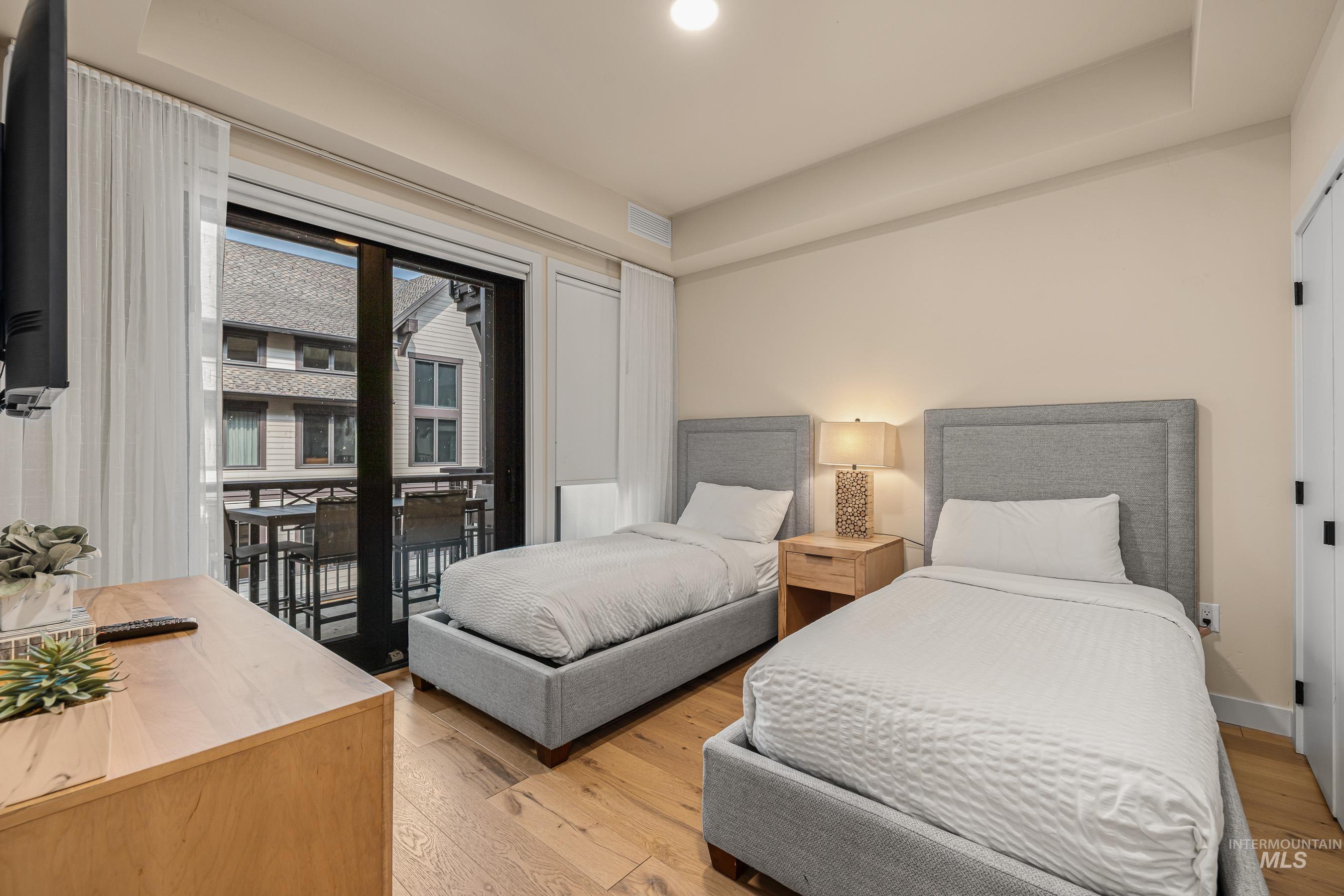 Bedroom featuring light wood-type flooring, a raised ceiling, access to outside, and recessed lighting