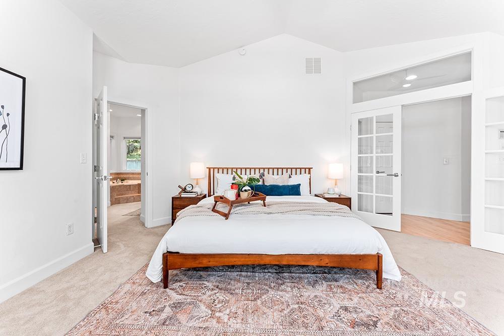 Bedroom featuring light carpet, french doors, and vaulted ceiling