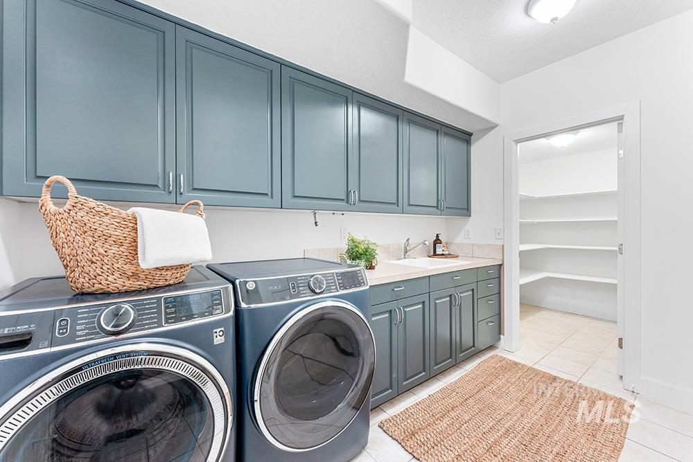 Laundry area with cabinet space, washer and dryer, and light tile patterned flooring