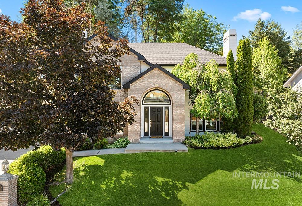 View of front of home featuring brick siding, a front yard, and a chimney