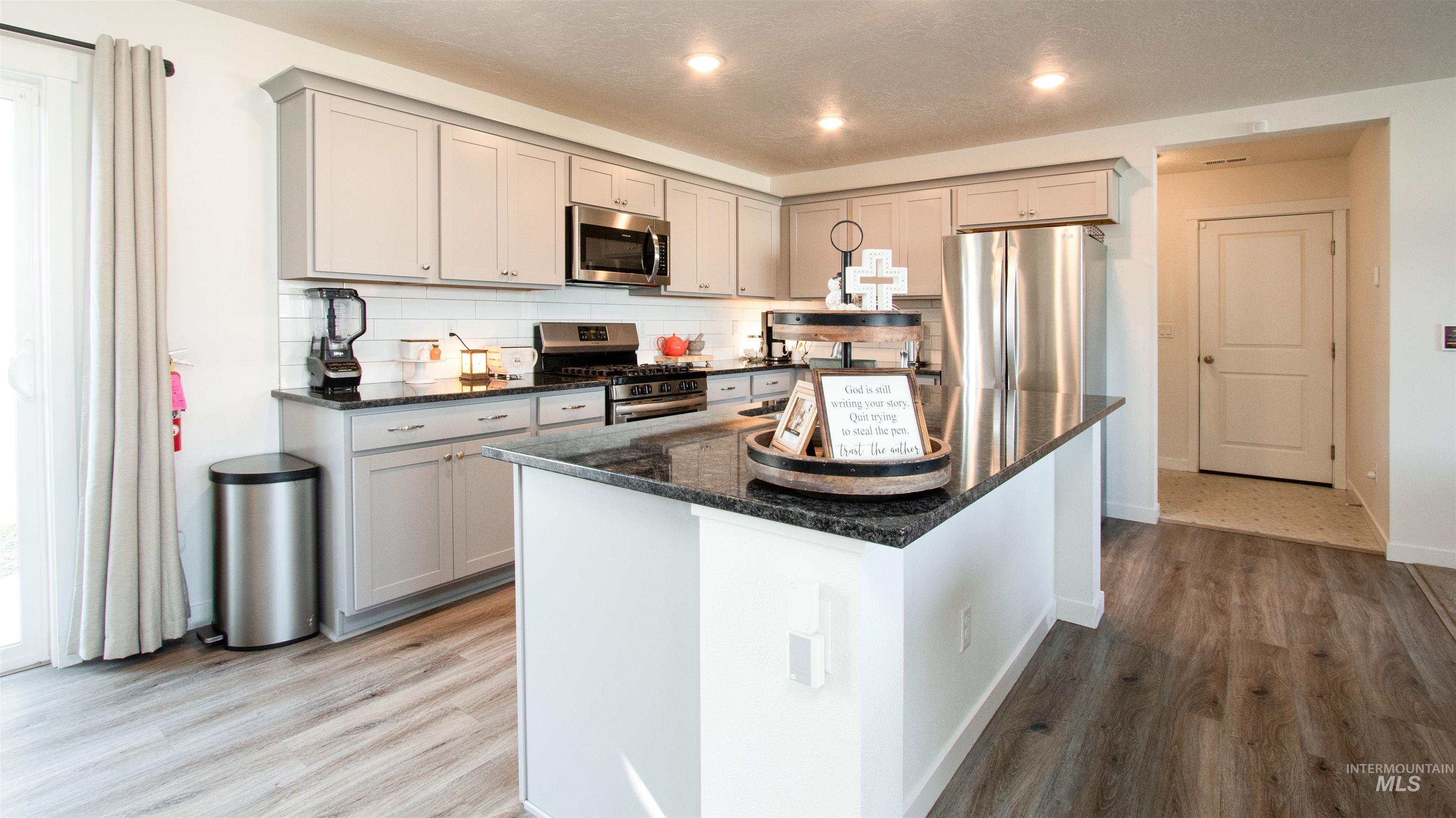 Kitchen featuring dark stone countertops, gray cabinetry, decorative backsplash, stainless steel appliances, and recessed lighting