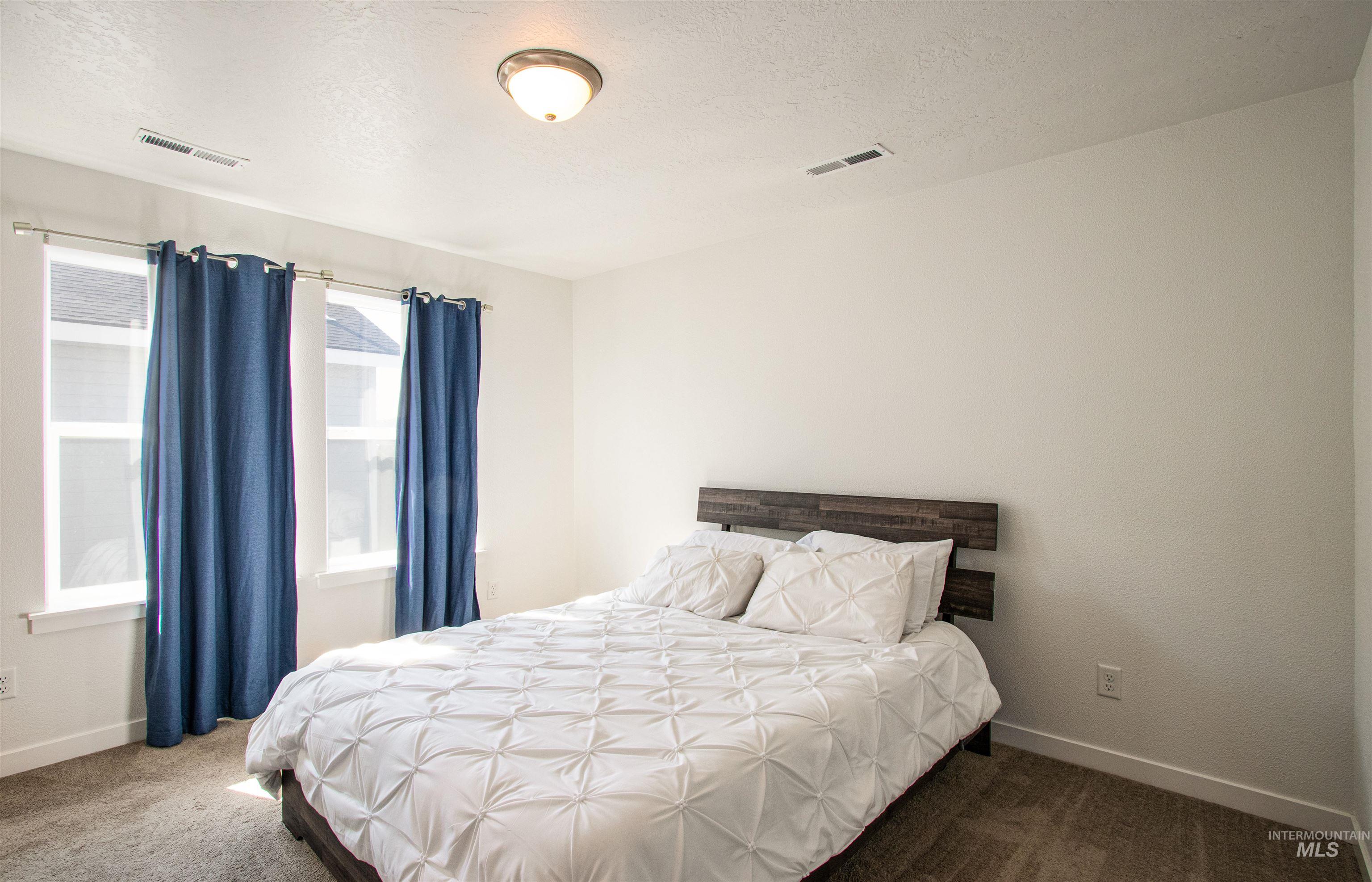 Carpeted bedroom featuring a textured ceiling and baseboards