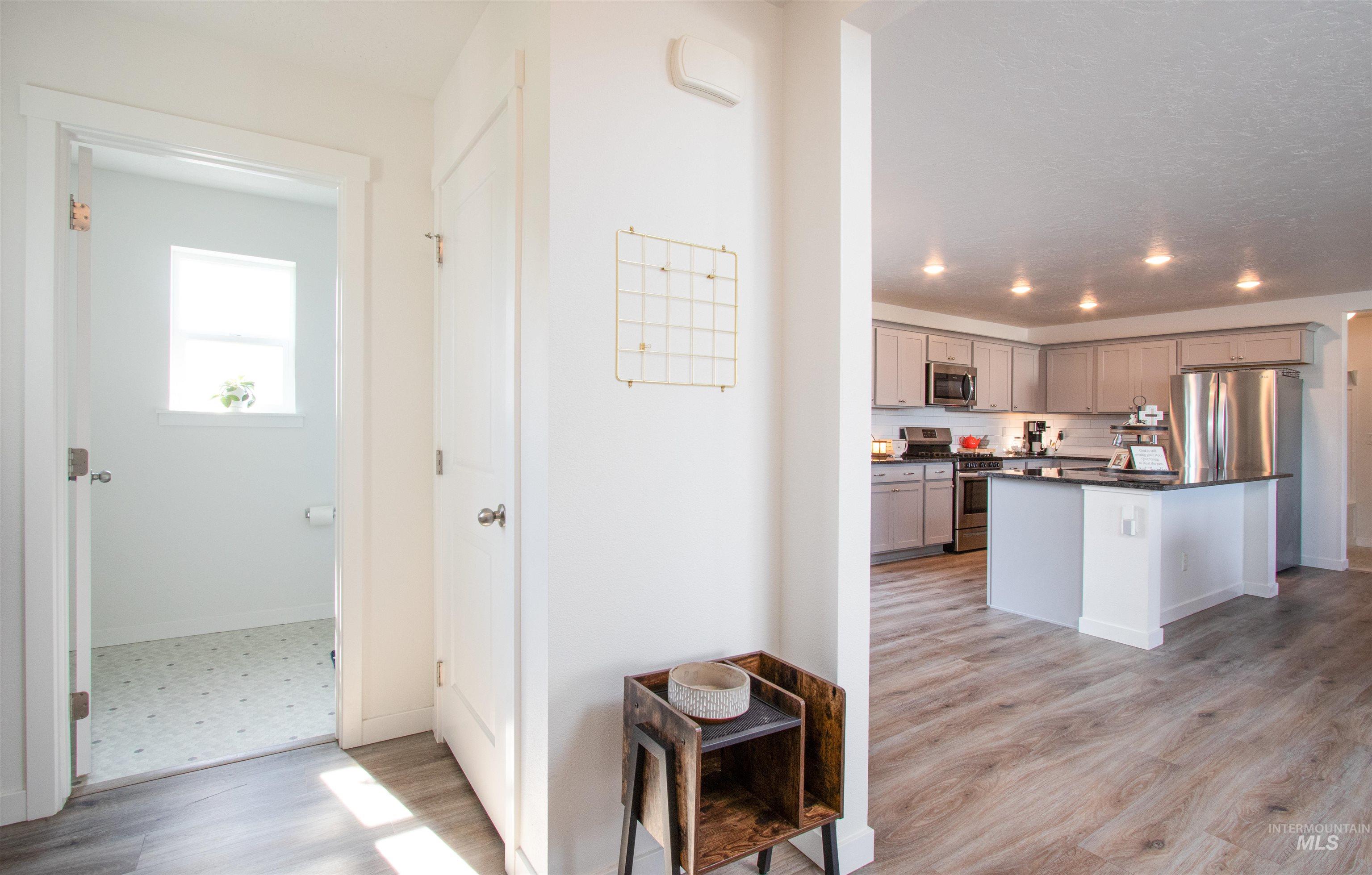 Kitchen featuring gray cabinets, a kitchen island, stainless steel appliances, light wood-type flooring, and backsplash
