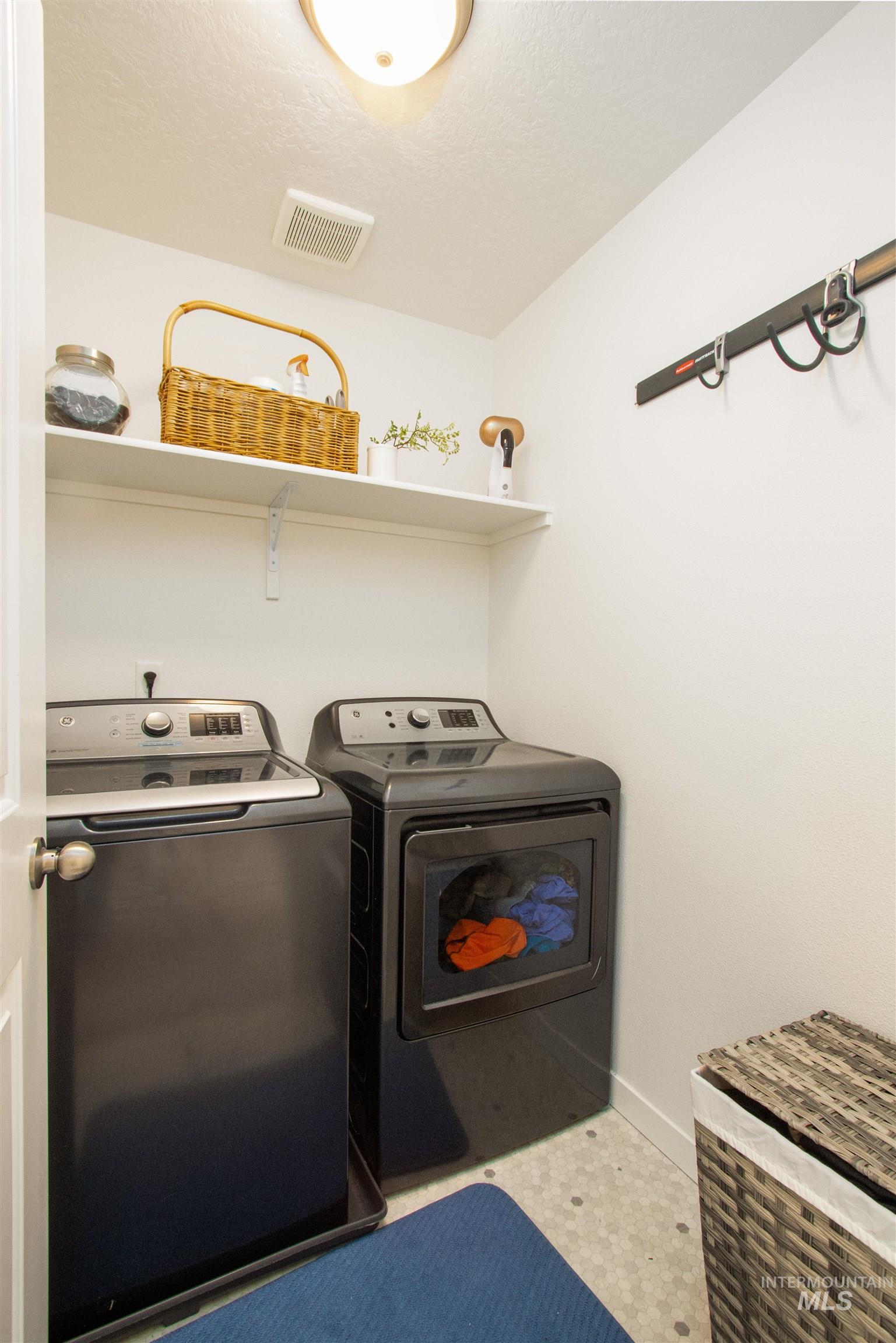 Washroom featuring washing machine and clothes dryer and a textured ceiling