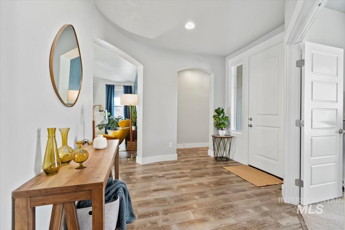 Hallway featuring arched walkways, light wood finished floors, and recessed lighting