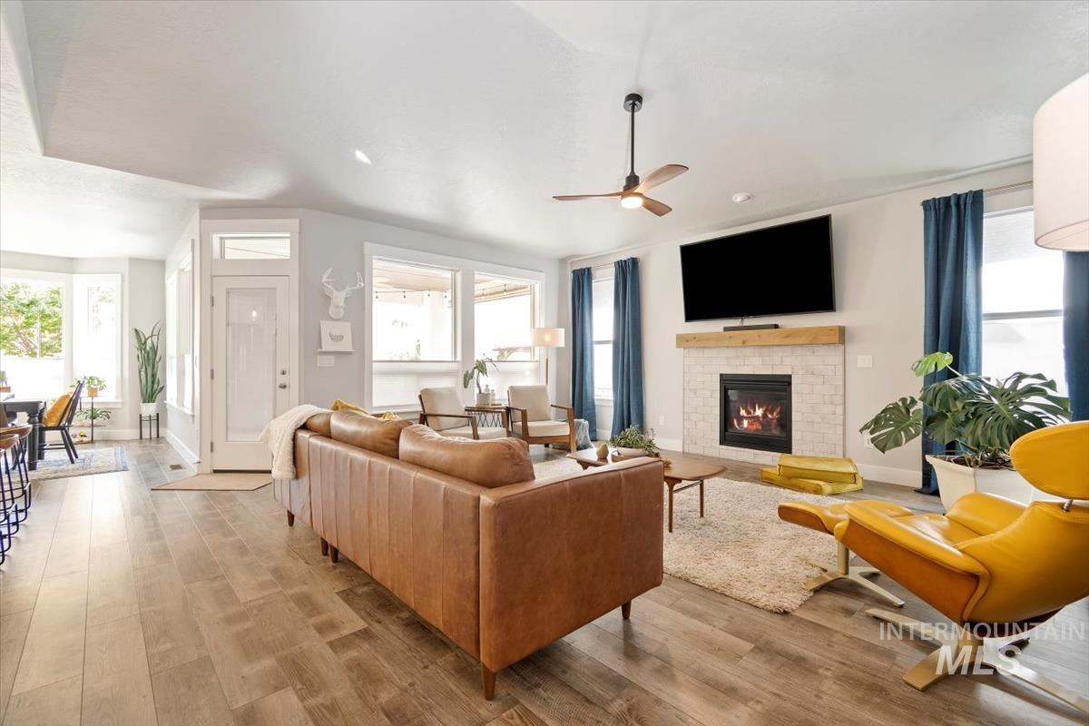Living room with a brick fireplace, light wood finished floors, and plenty of natural light