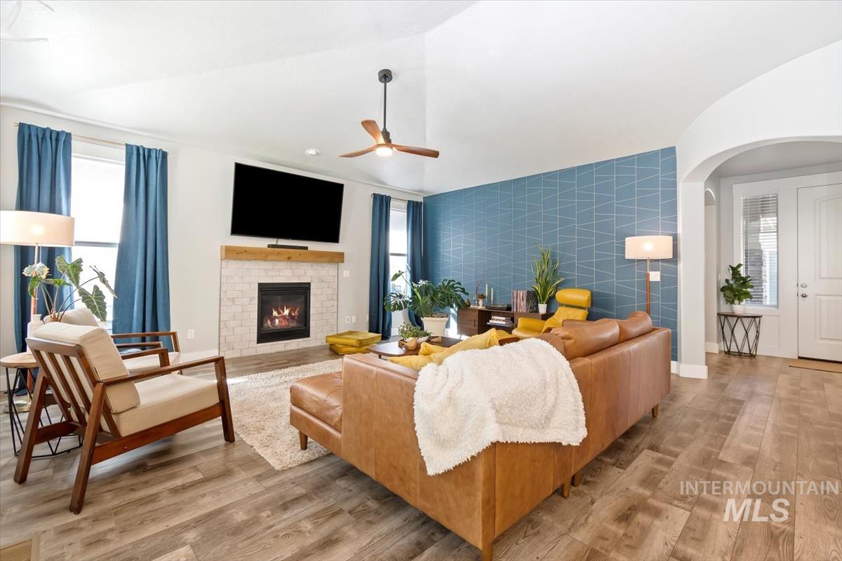 Living area featuring healthy amount of natural light, arched walkways, light wood-style floors, and tile walls