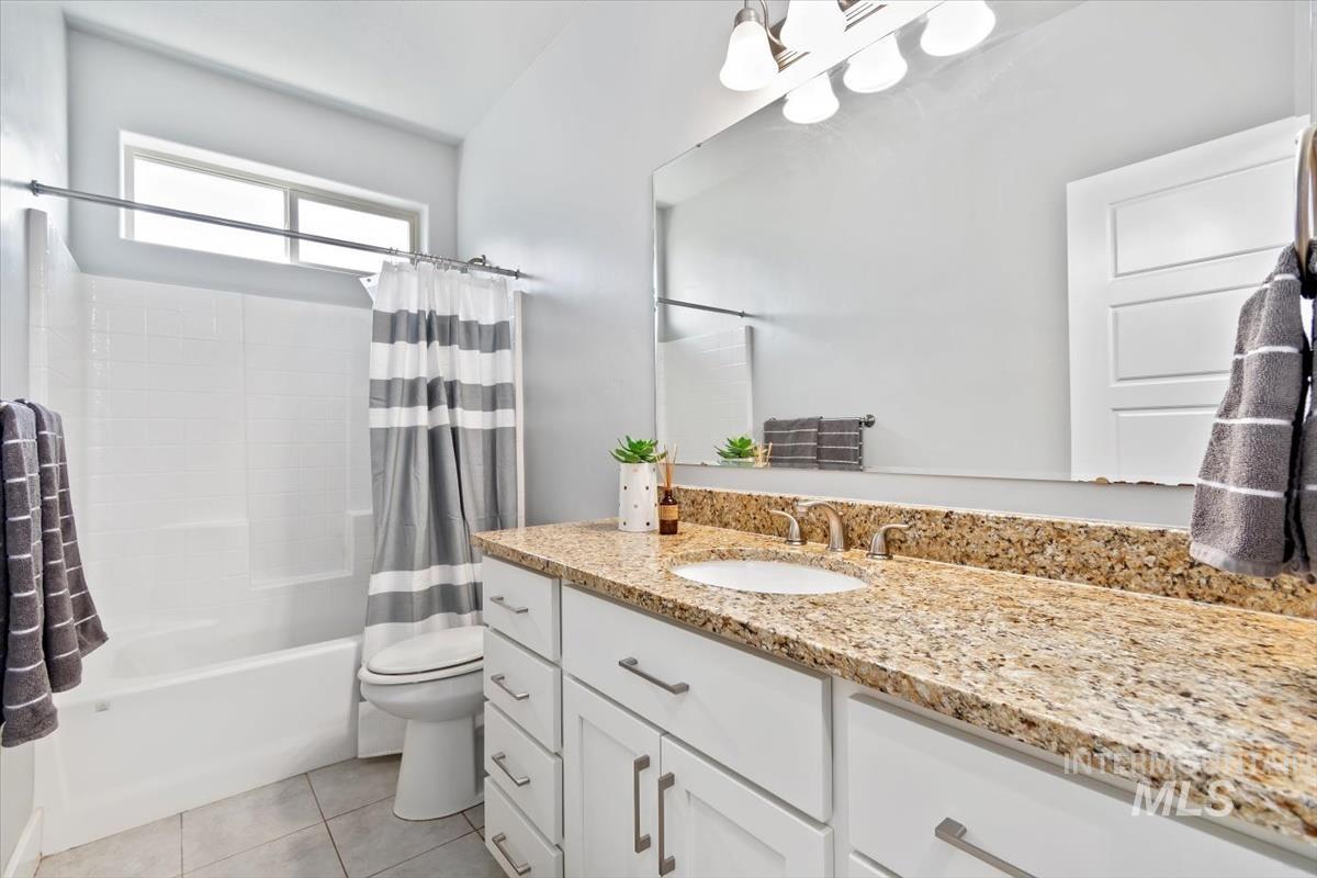 Full bath featuring shower / bath combo, vanity, and light tile patterned floors