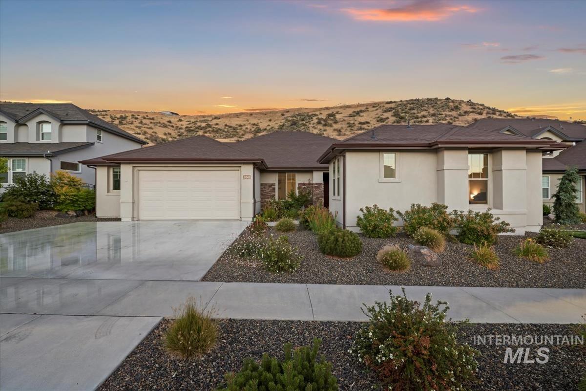 View of front of house featuring stucco siding, driveway, a mountain view, and a garage