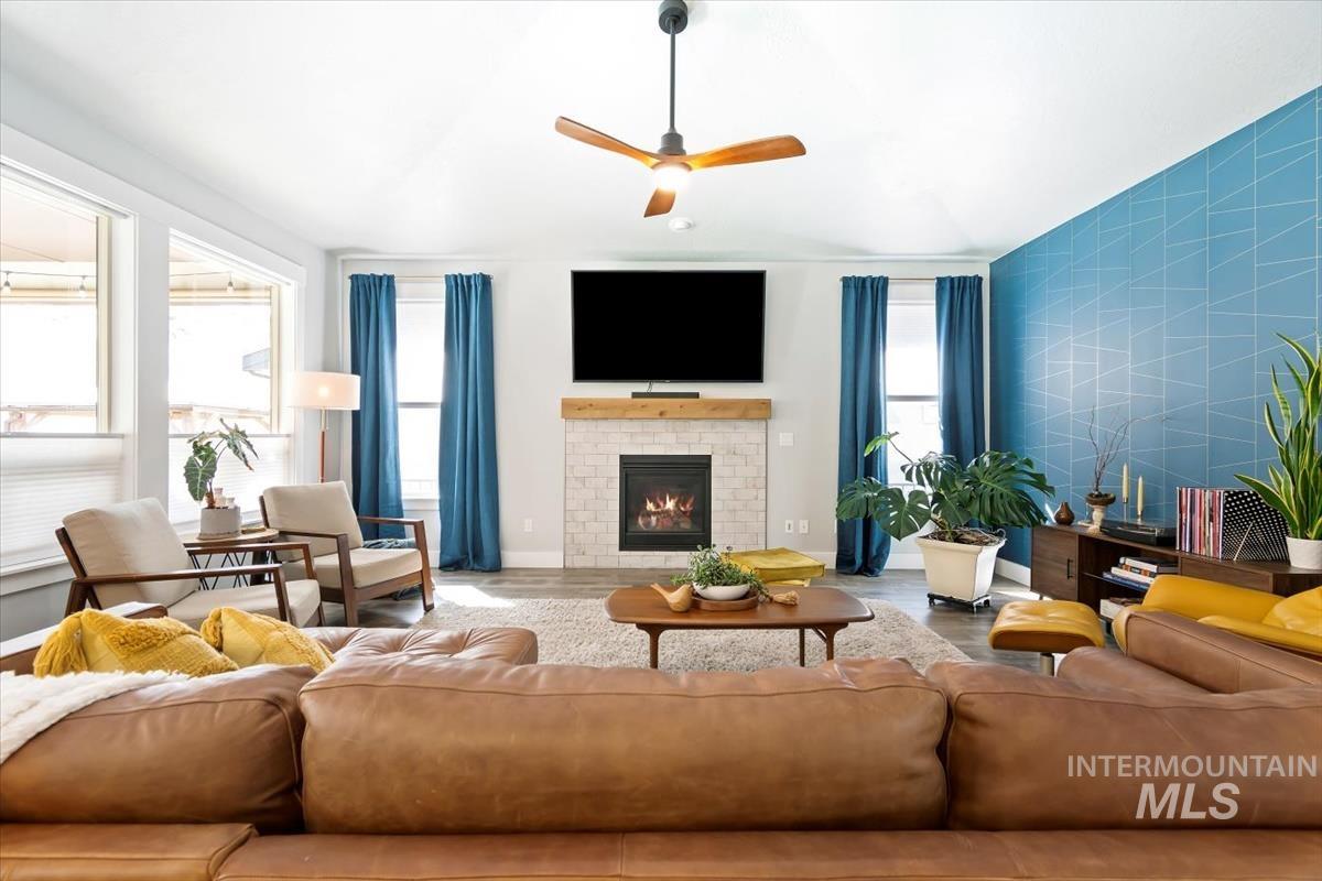 Living area with a fireplace, ceiling fan, and wood finished floors