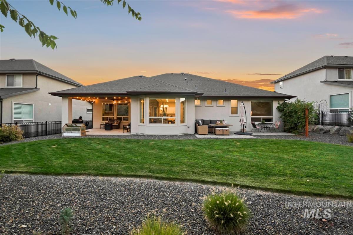 Back of house at dusk featuring an outdoor living space, a patio, stucco siding, and a shingled roof